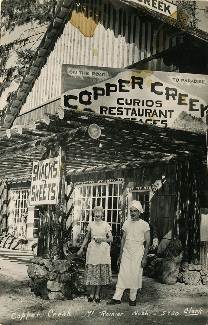 A couple of people standing in front of a restaurant called copper creek