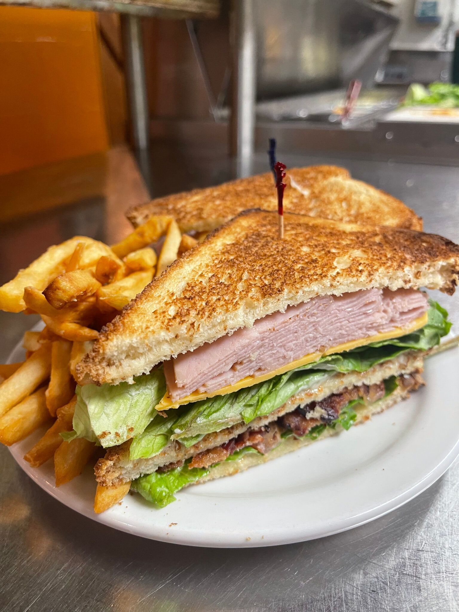 A club sandwich and french fries on a white plate.