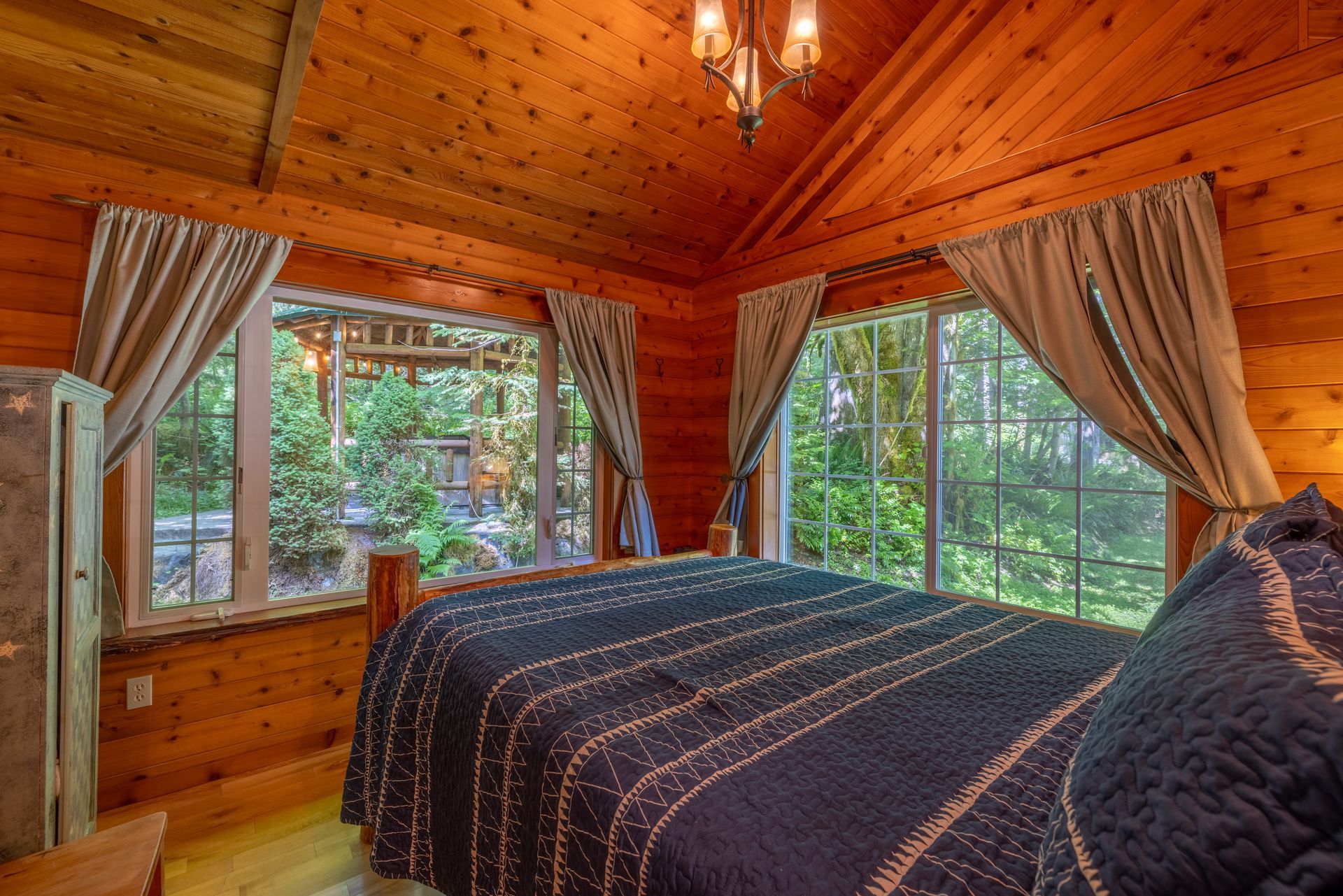 A rocking chair with a green blanket on it is sitting in front of a window.