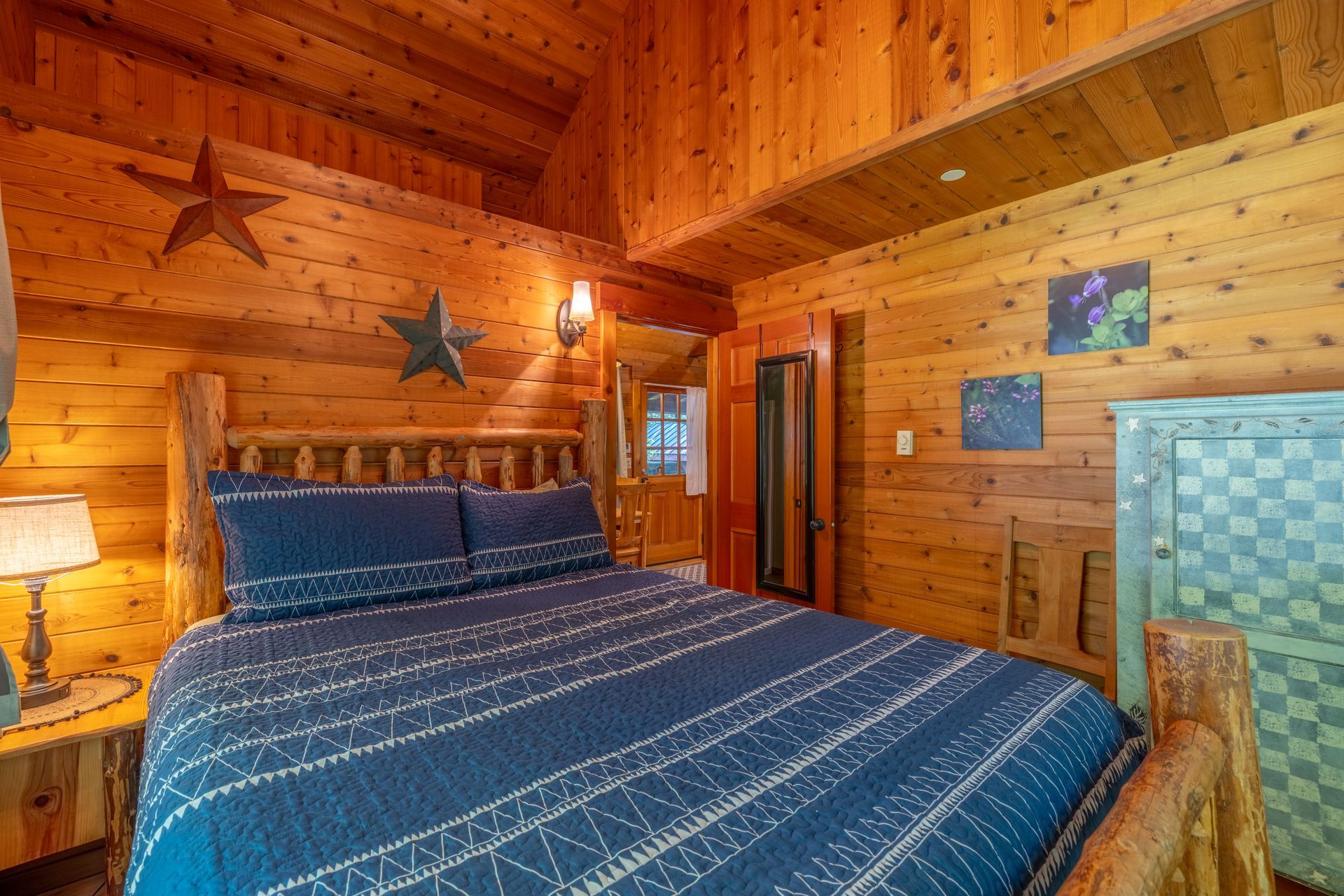 A bedroom in a log cabin with a bed and a large window.