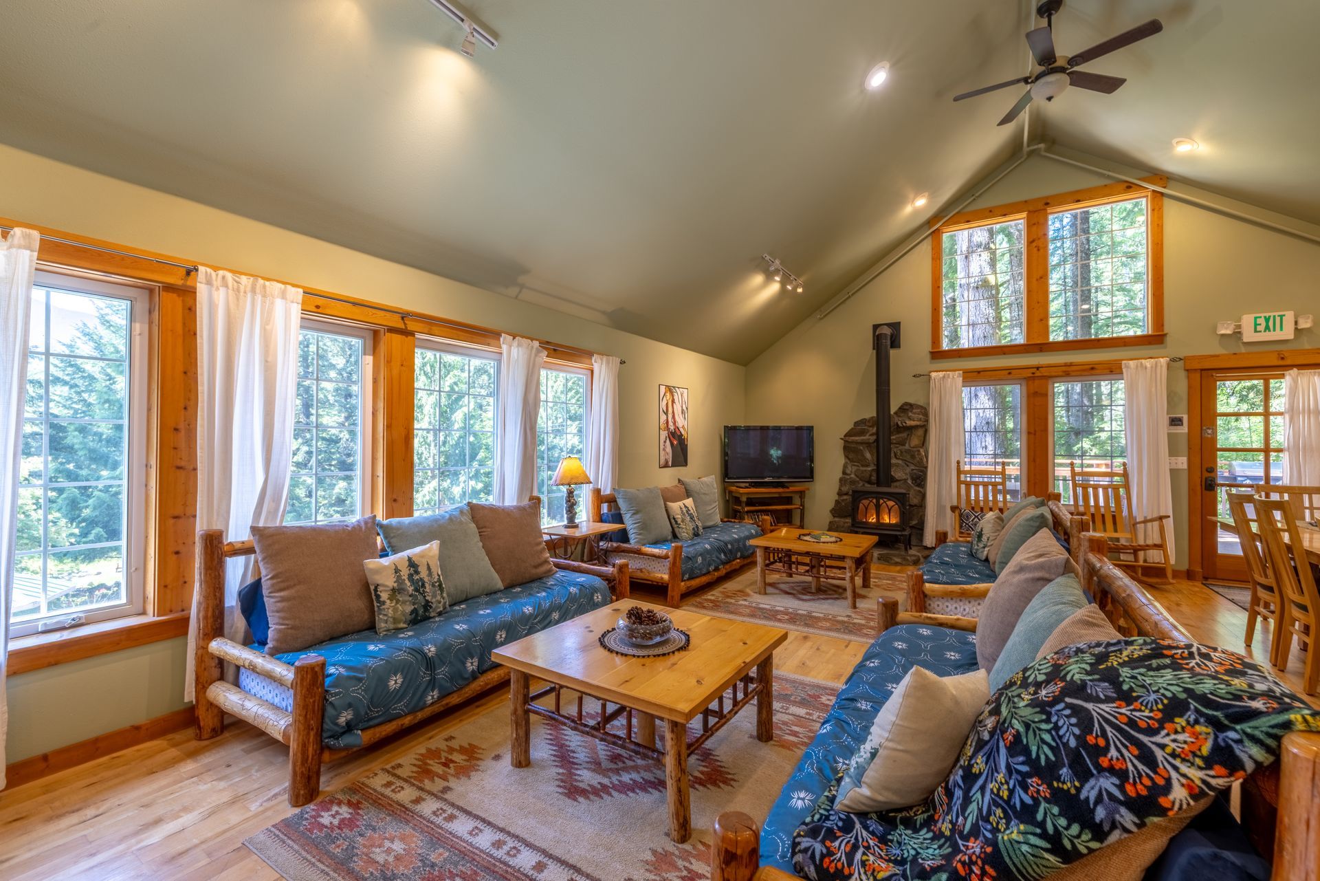 Spacious living room in a cabin with rustic wooden furniture, large windows, a fireplace, and two blue futons.