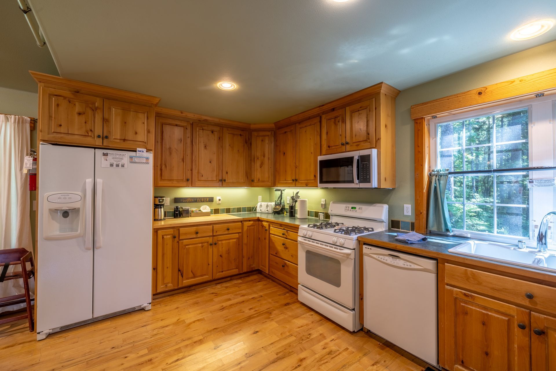 Wooden kitchen with wood cabinets, white appliances, and a window with natural light.