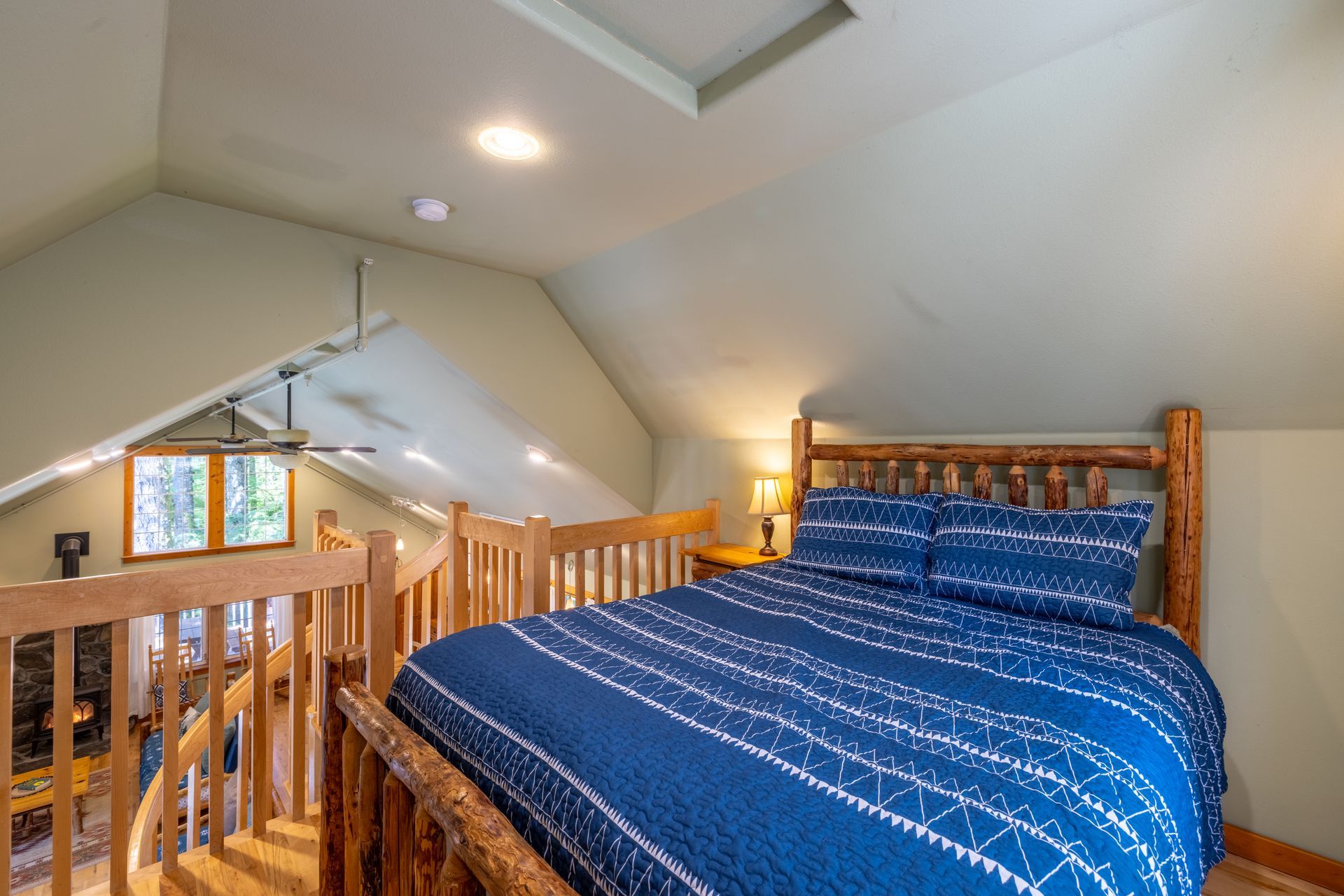 A bed with a quilt on it is in a room with a wooden railing.