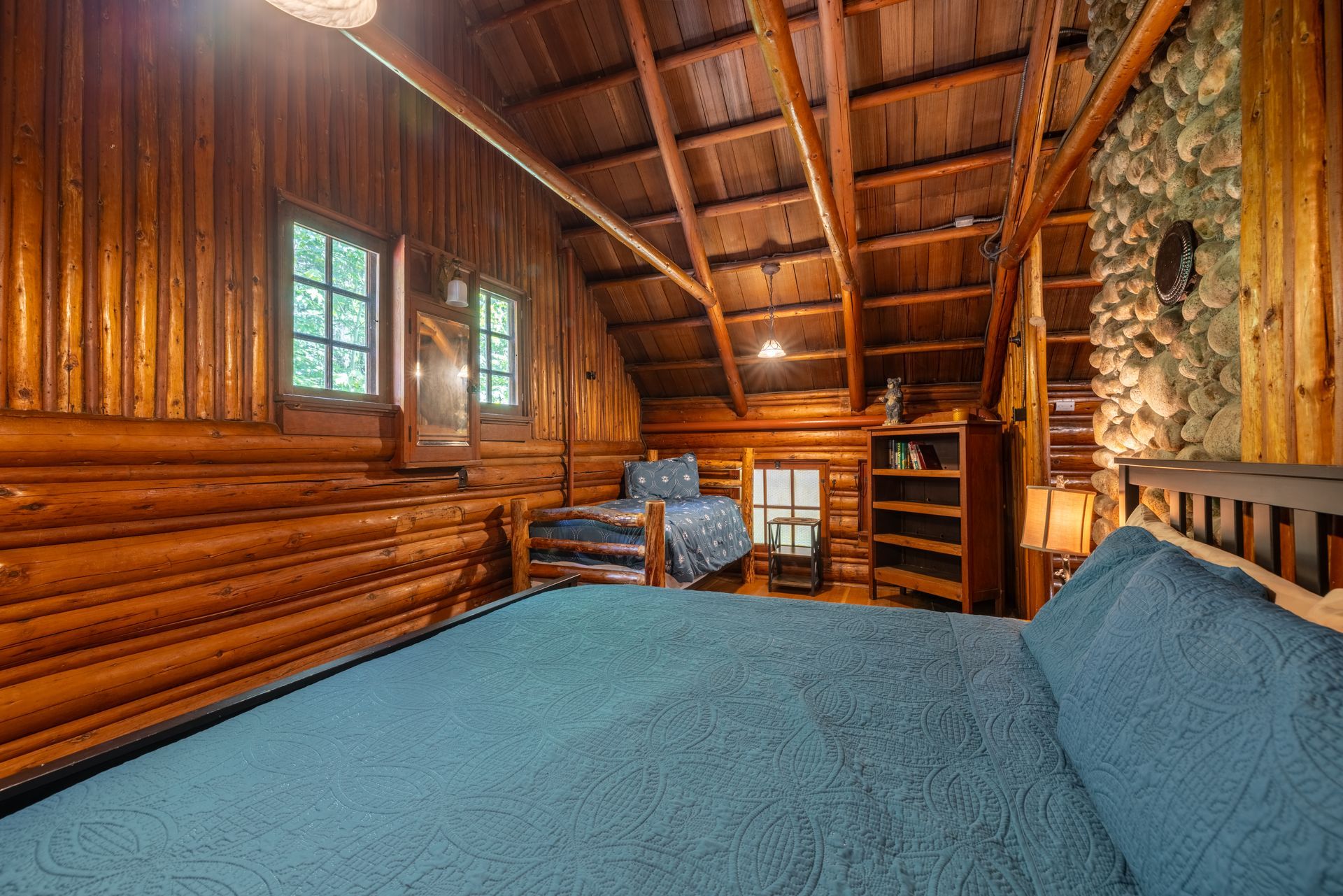 Wooden cabin porch with a view, featuring a blue floor, open doorways, and a bench.