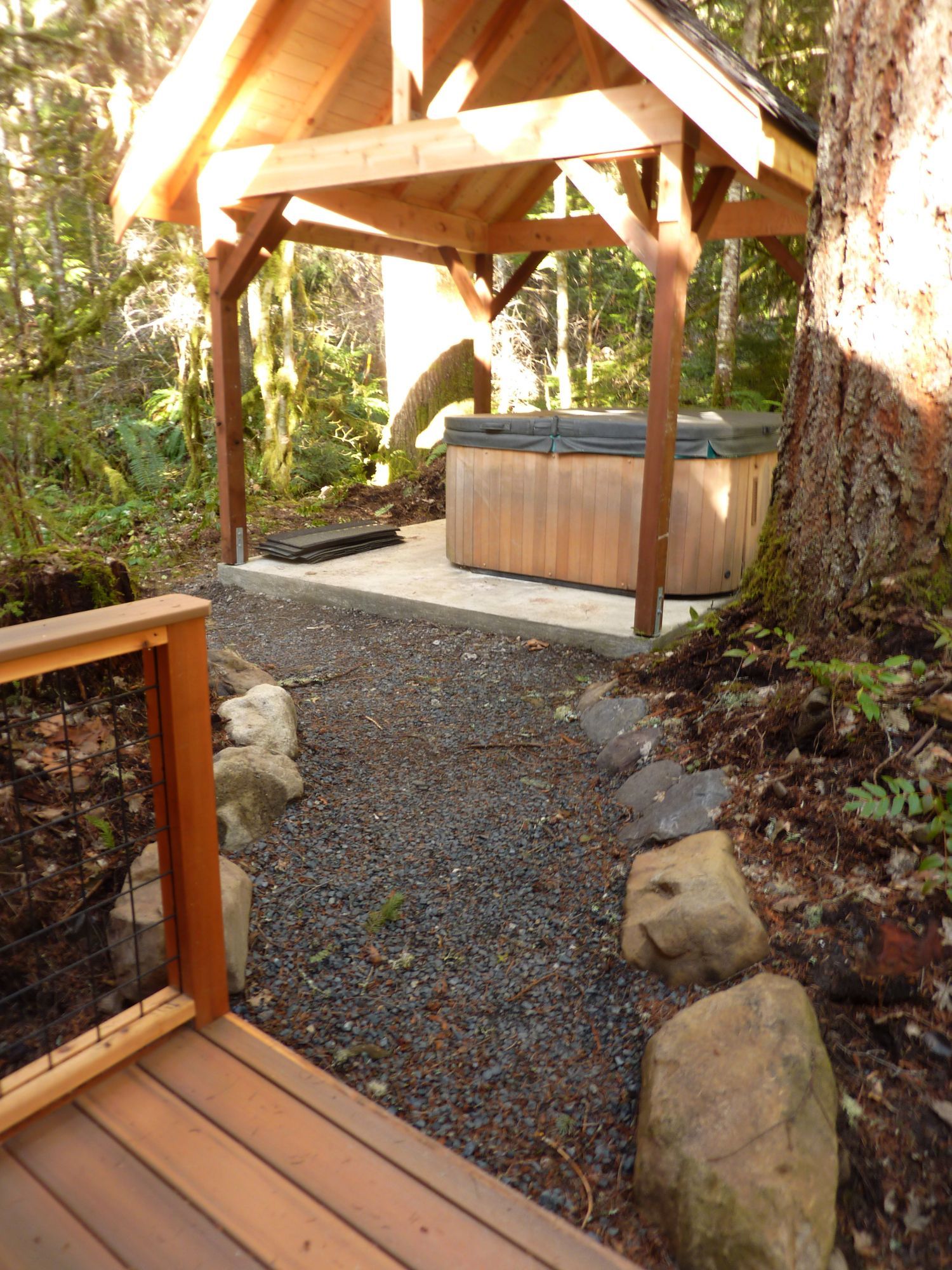 A wooden gazebo with a hot tub underneath it