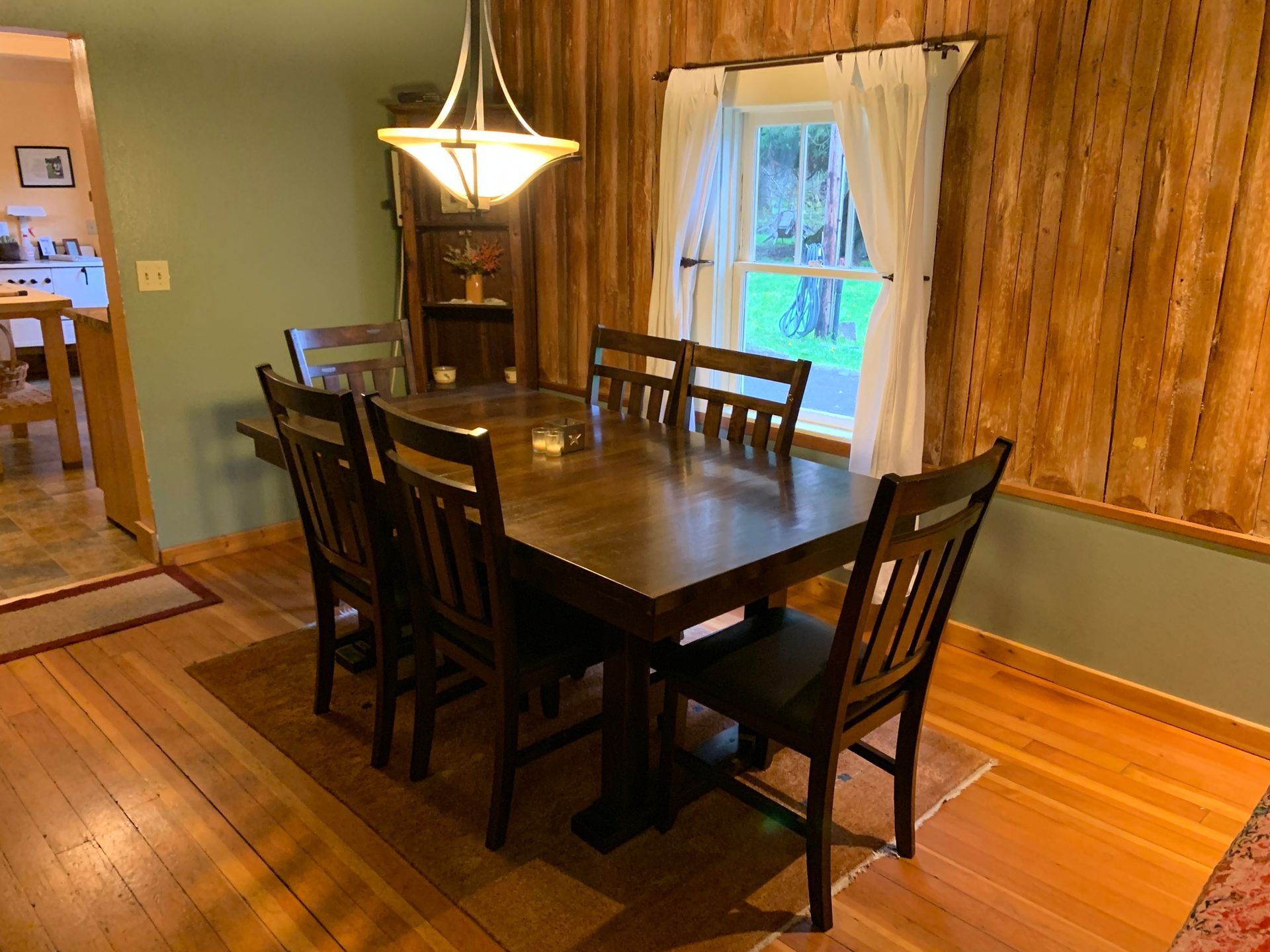 A dining room with a table and chairs and a window.