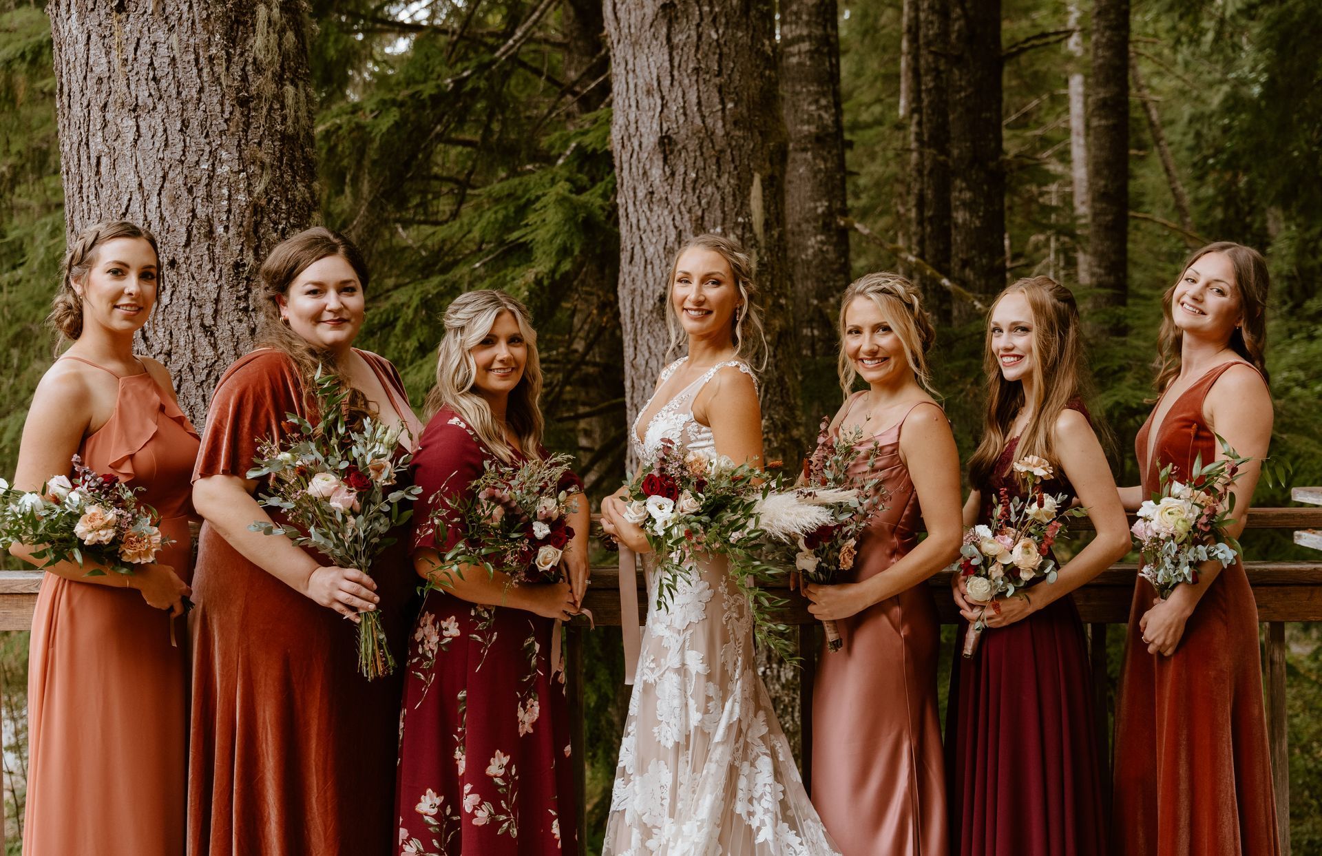 A bride and her bridesmaids are posing for a picture in front of a log cabin.