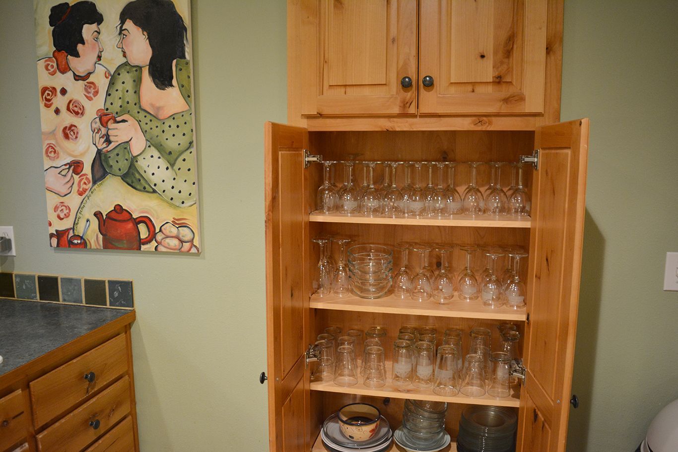 A wooden cabinet filled with wine glasses and plates