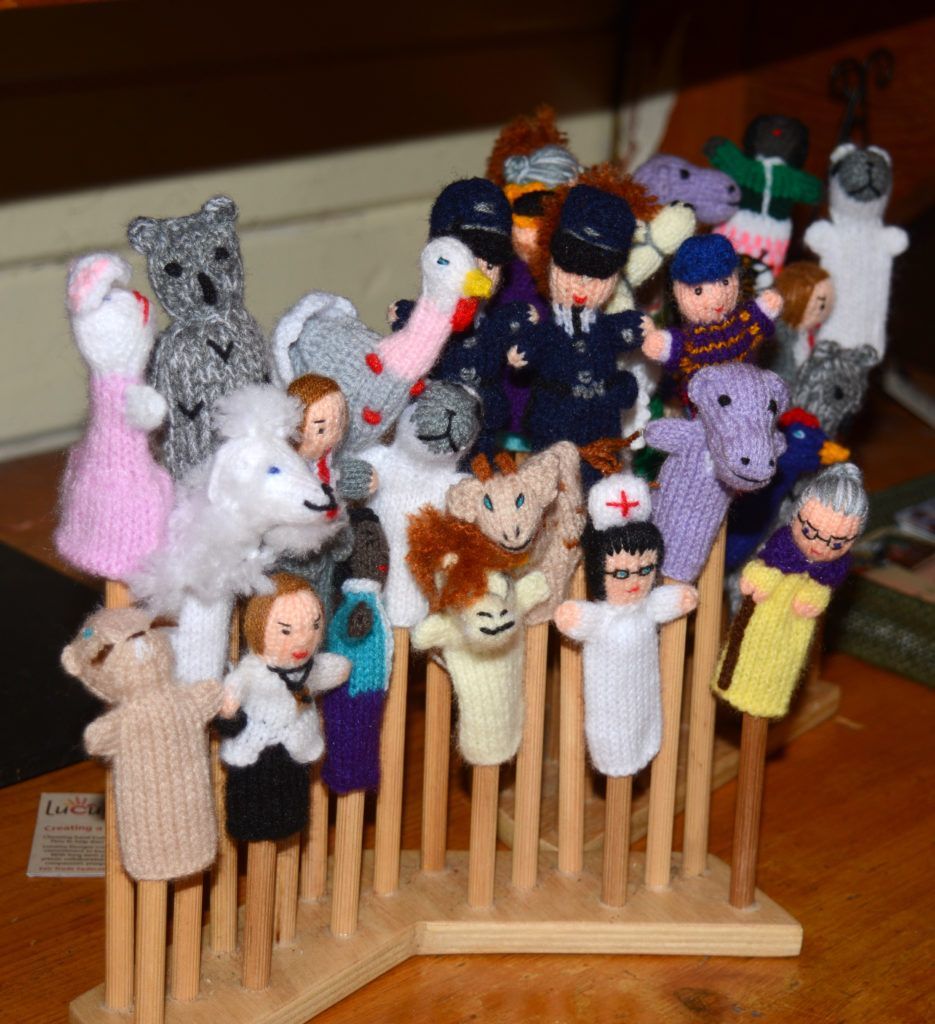 A bunch of finger puppets are sitting on a wooden stand