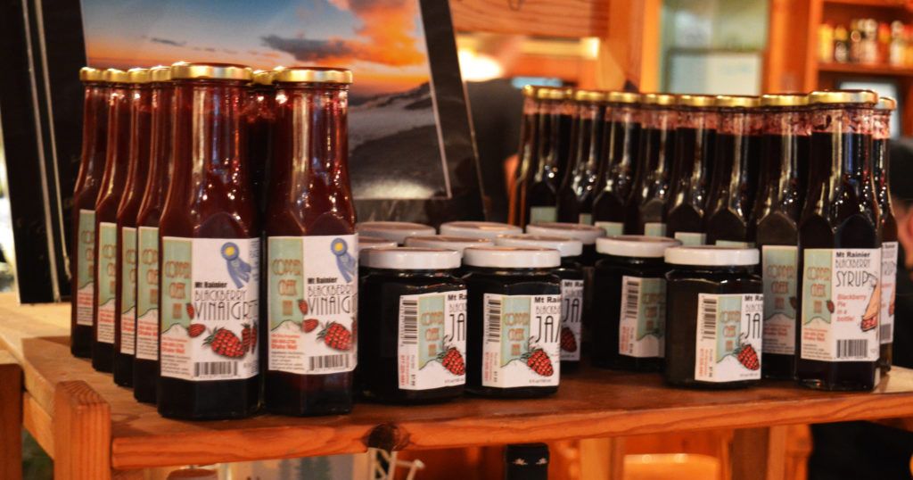 A shelf filled with bottles and jars of strawberry sauce.