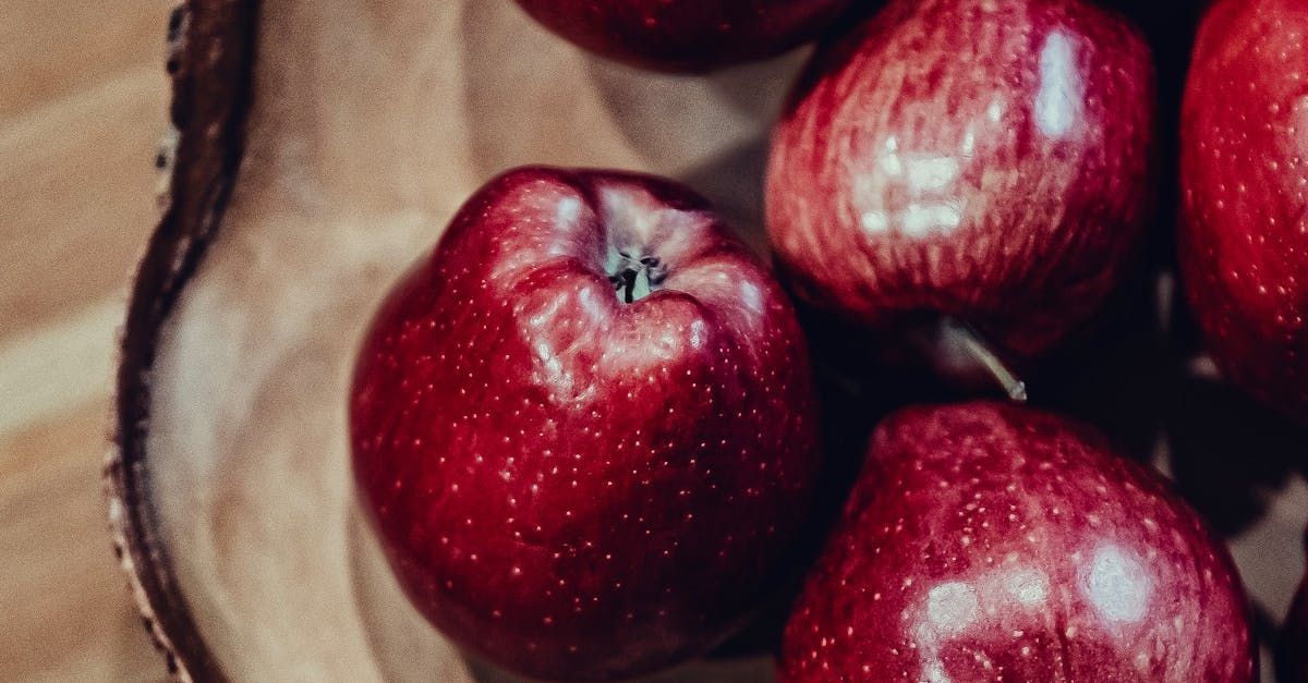 A bowl filled with red apples on a wooden table.