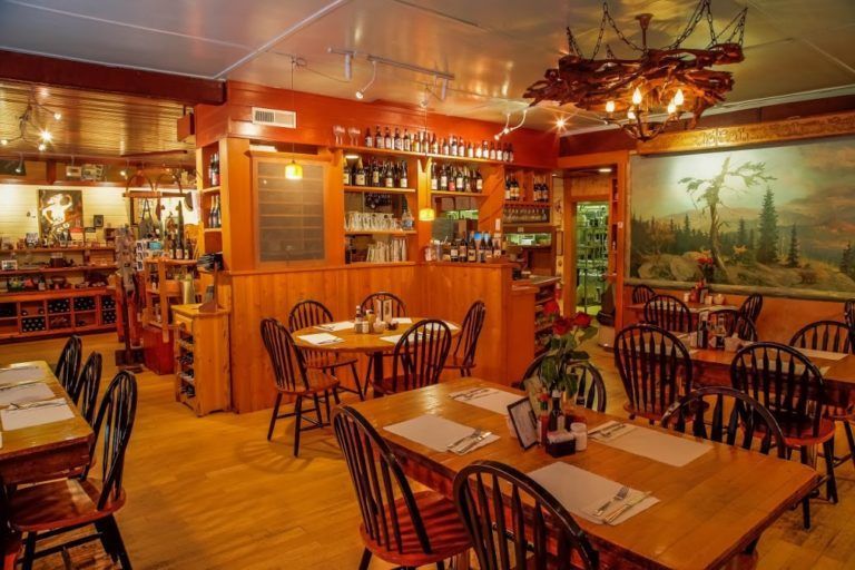 A restaurant with tables and chairs and a large picture on the wall