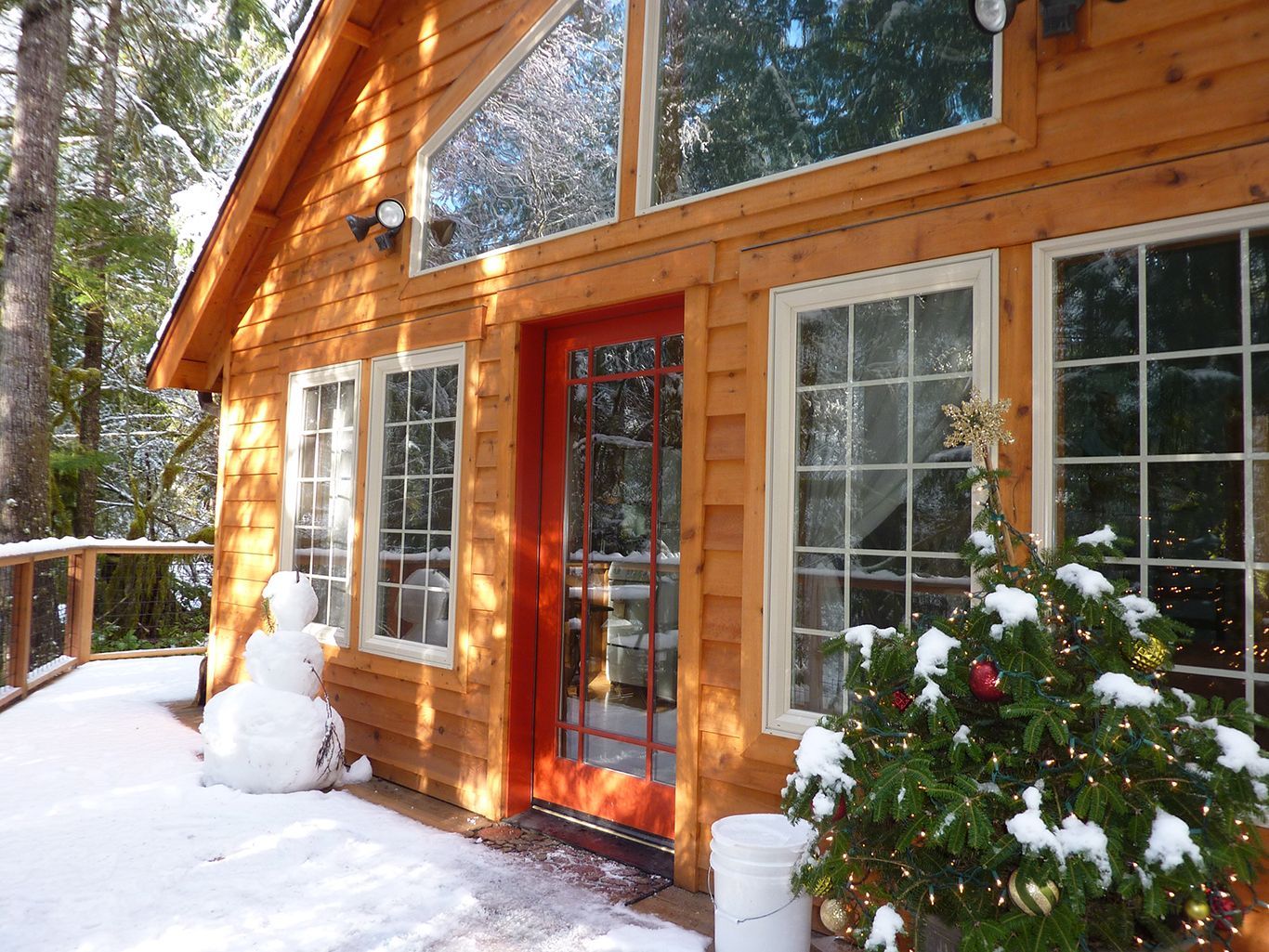 A house with a red door and a snowman in front of it