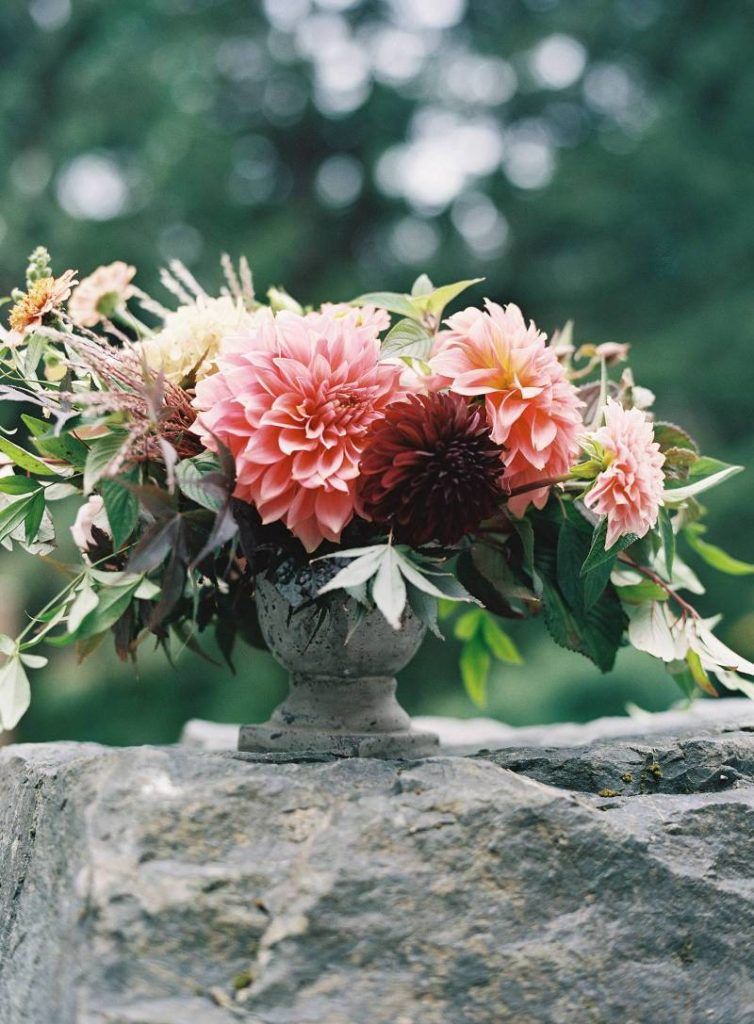 A vase filled with pink flowers is sitting on a rock.