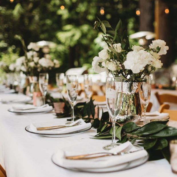 A long table with plates , glasses , and flowers on it