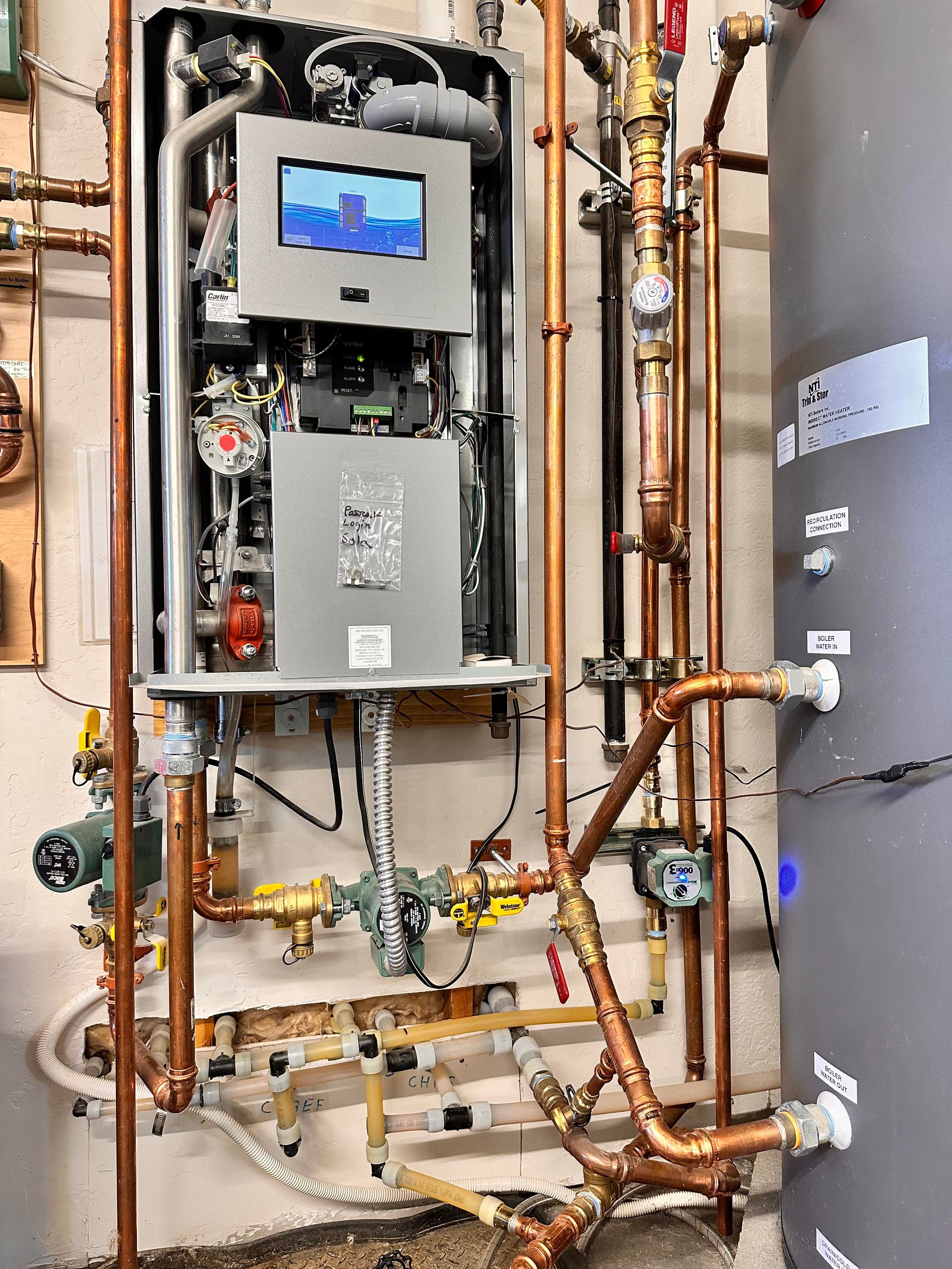 Copper pipes and a complex heating system with digital display installed on a wall.