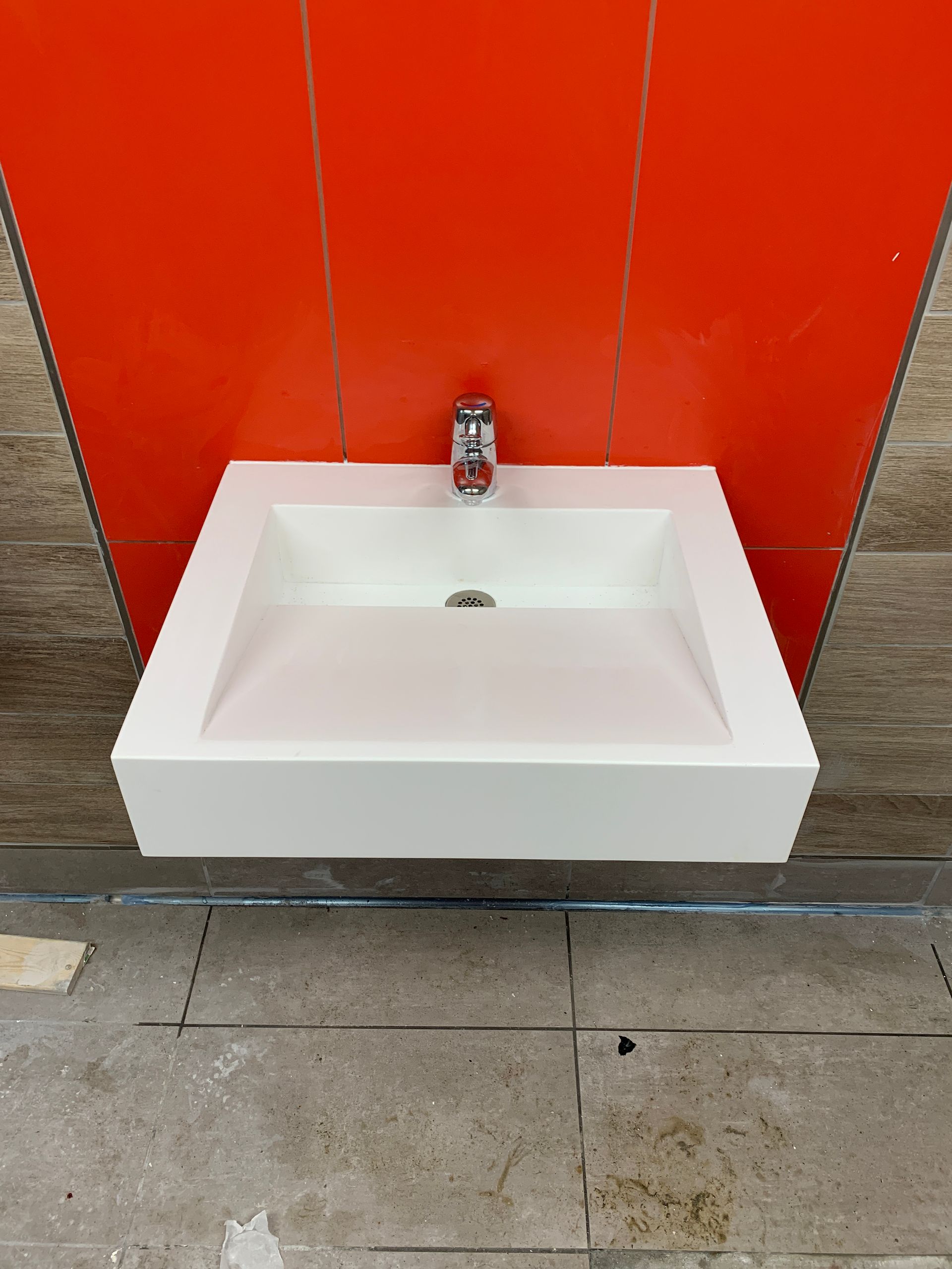 White rectangular sink with chrome faucet against an orange wall.