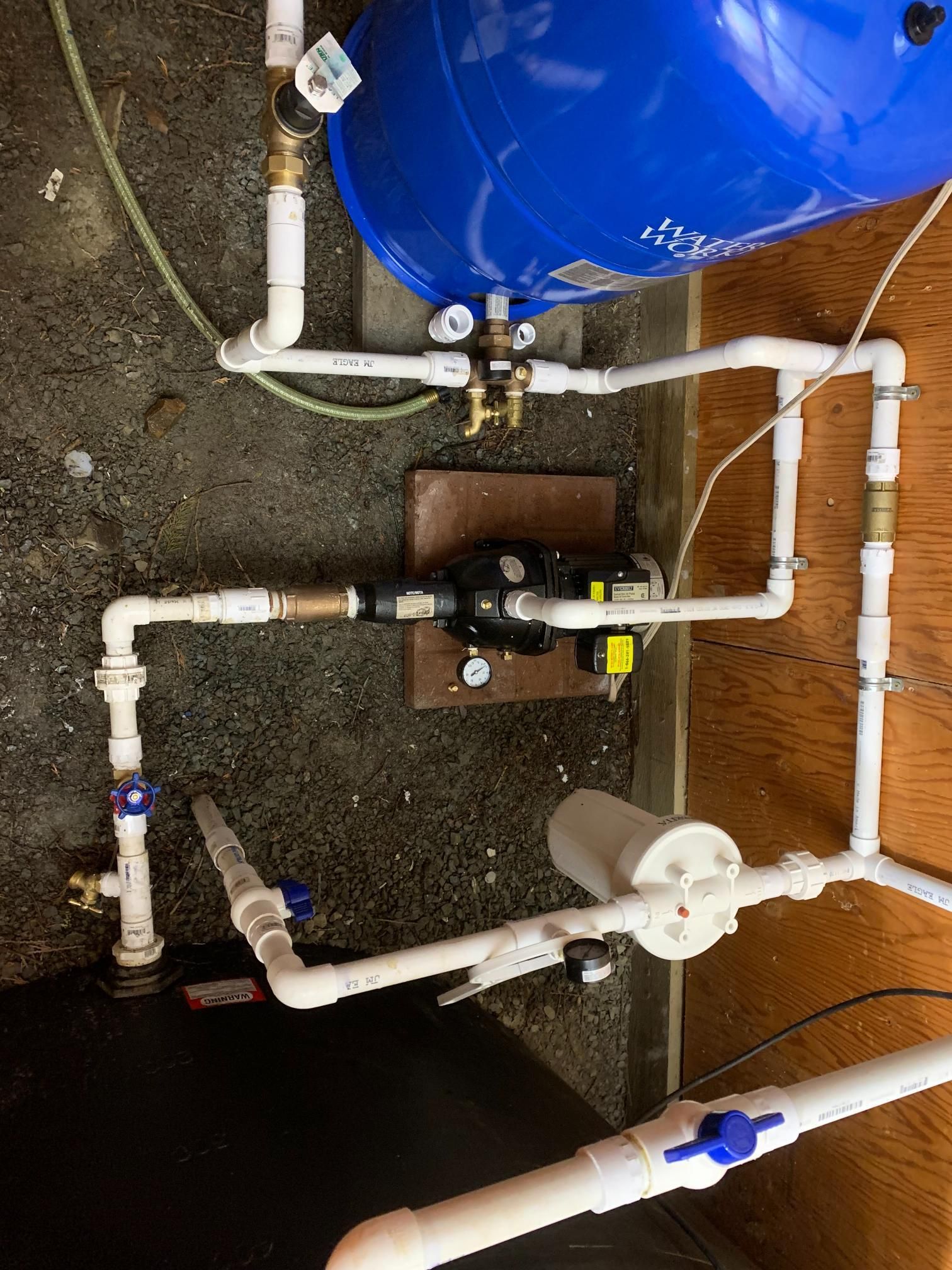 Plumbing system with blue tank and white pipes, valves, and a black pump.