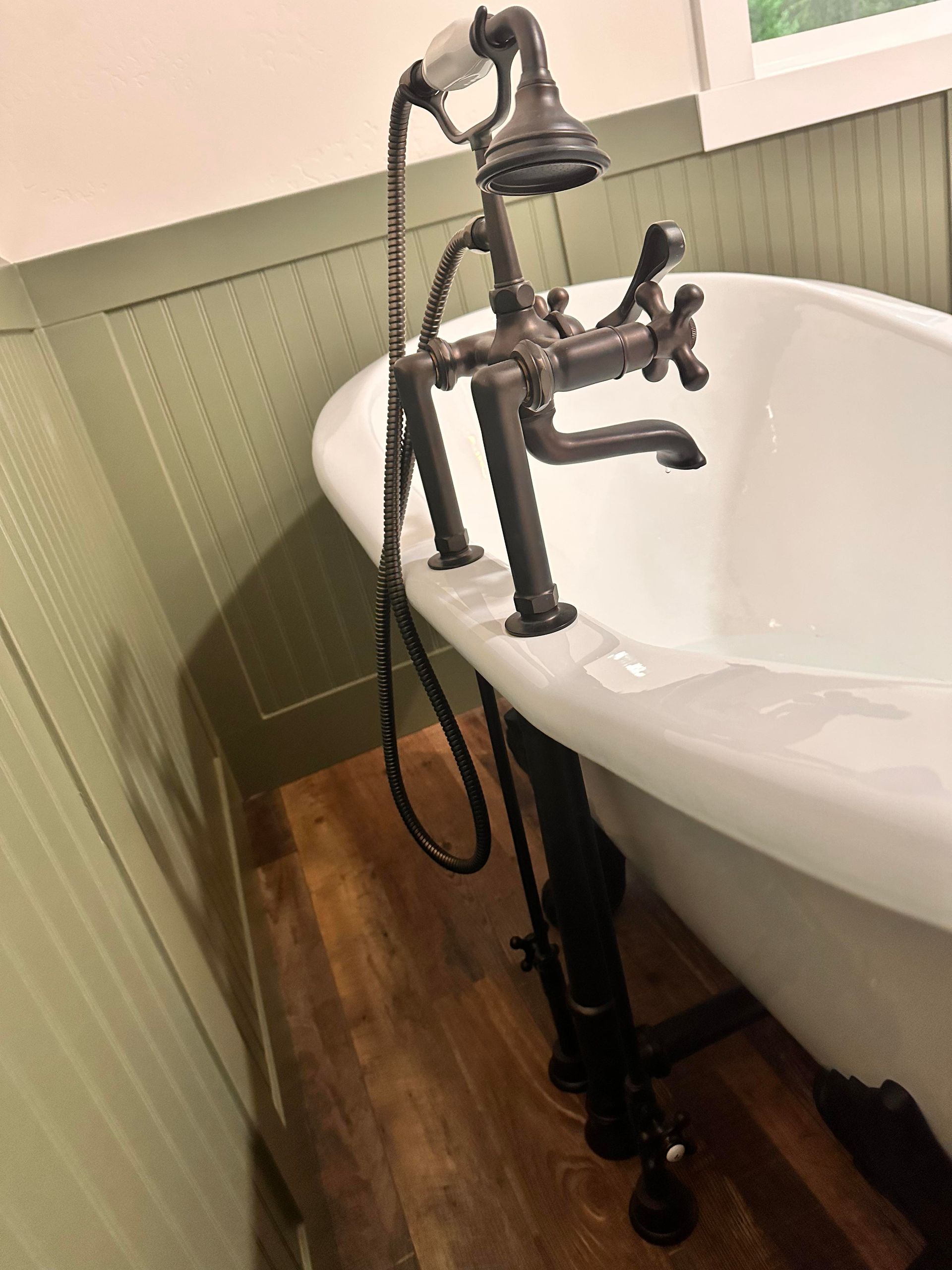 Antique claw-foot bathtub with black fixtures and handheld showerhead.
