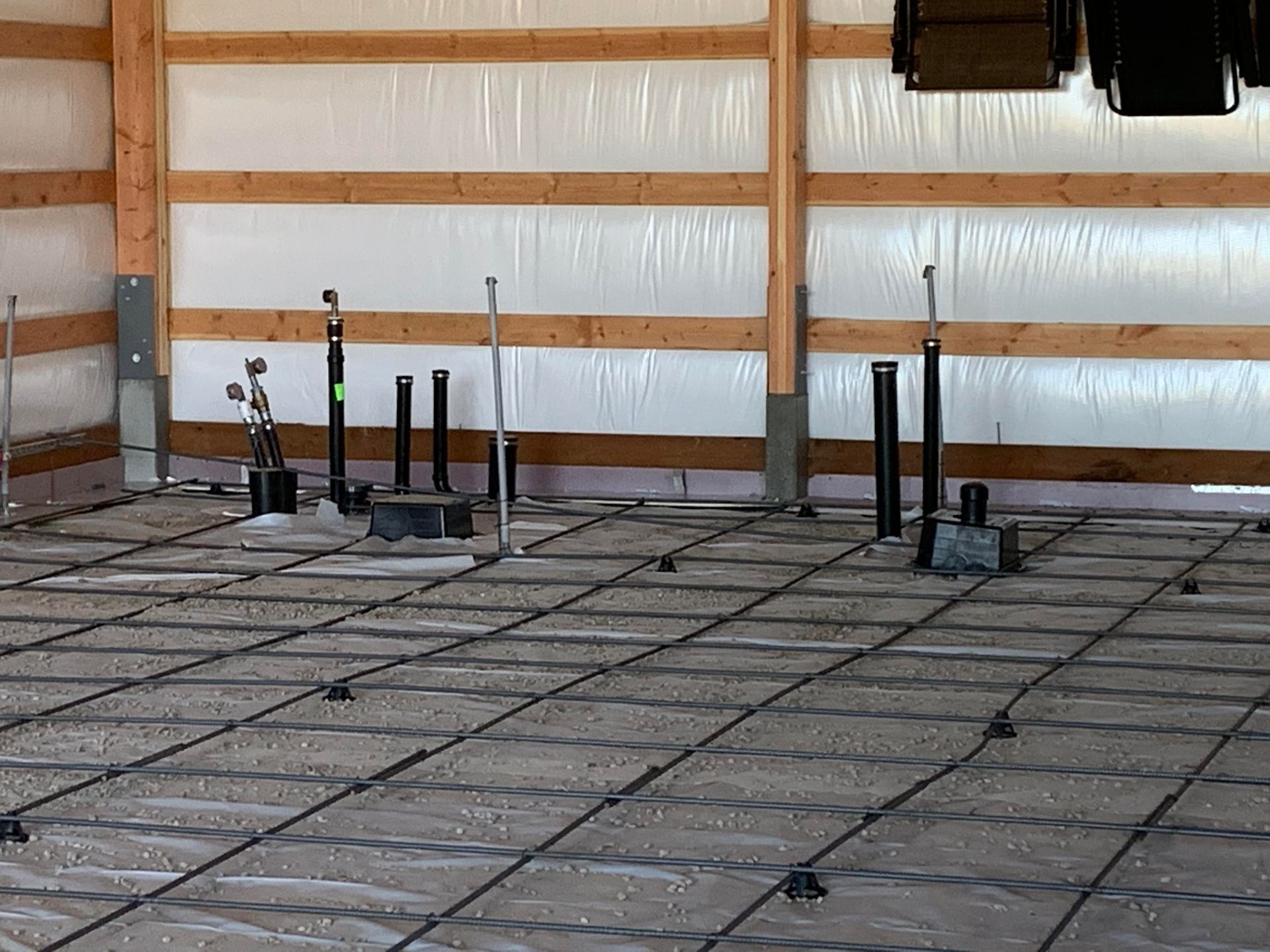 Interior of a building under construction with rebar grid laid on gravel, ready for concrete floor.
