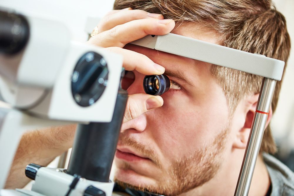 A man is looking through a microscope at his eye