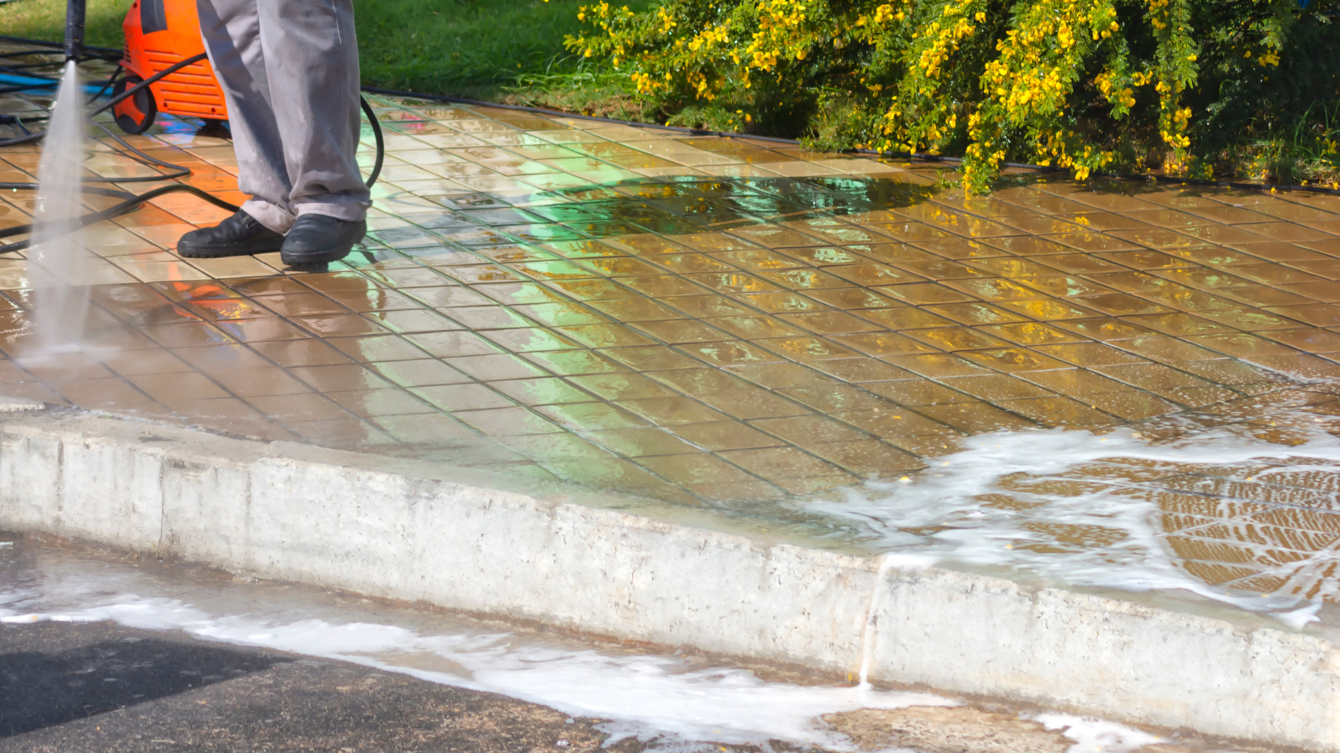 A man is using a high pressure washer to clean a sidewalk