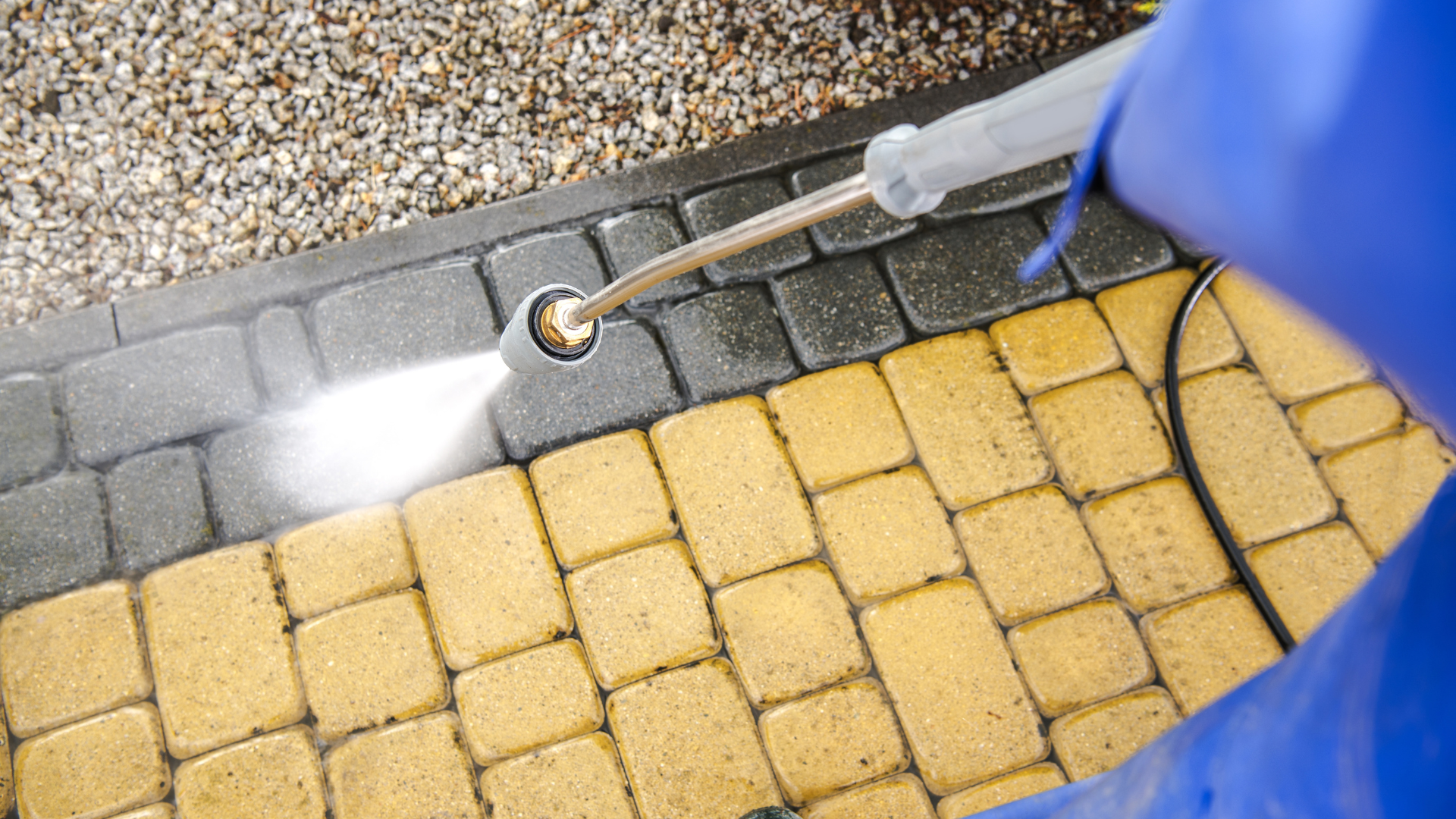 A person is cleaning a brick walkway with a high pressure washer