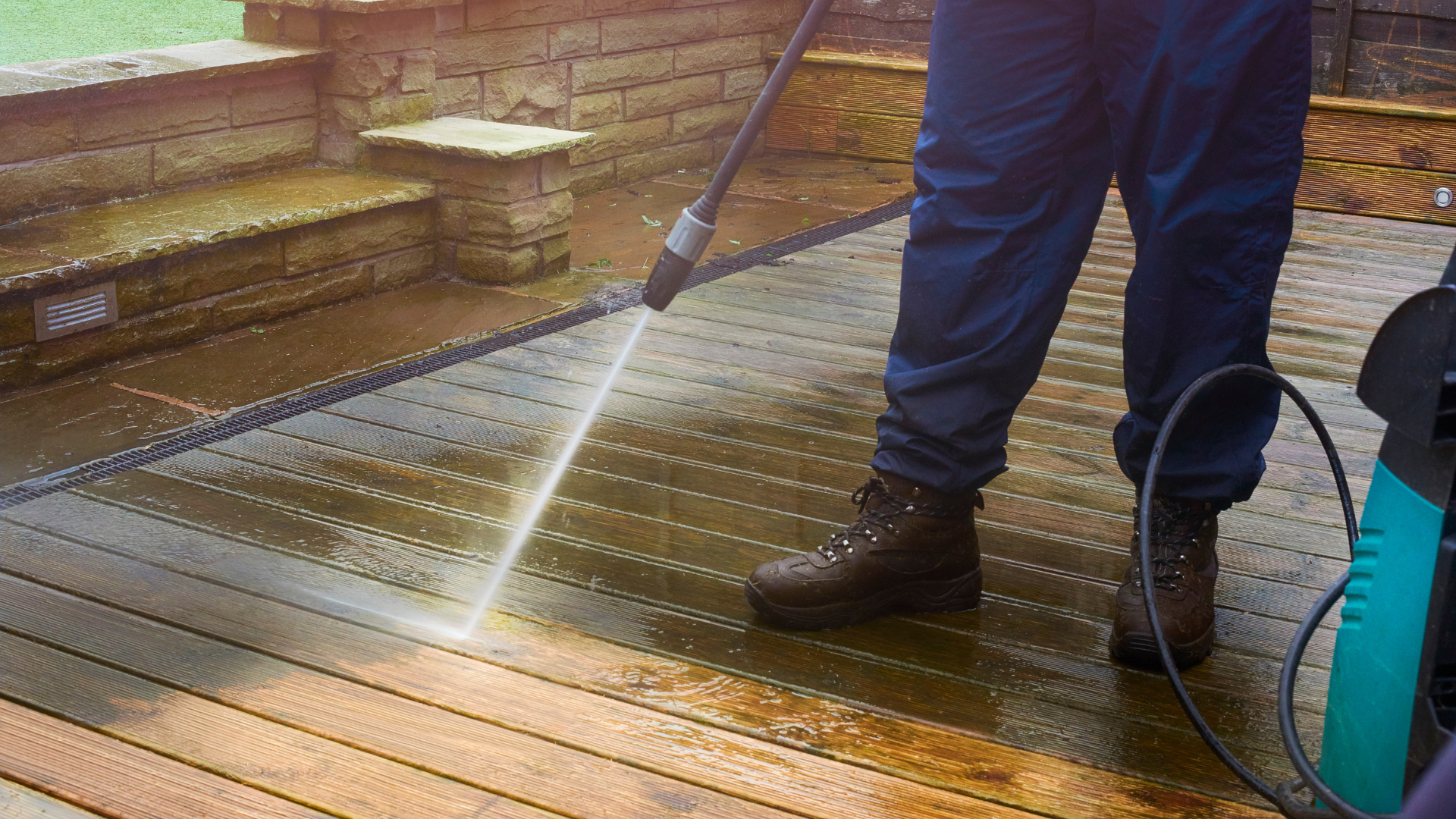 A man is using a high pressure washer to clean a wooden deck