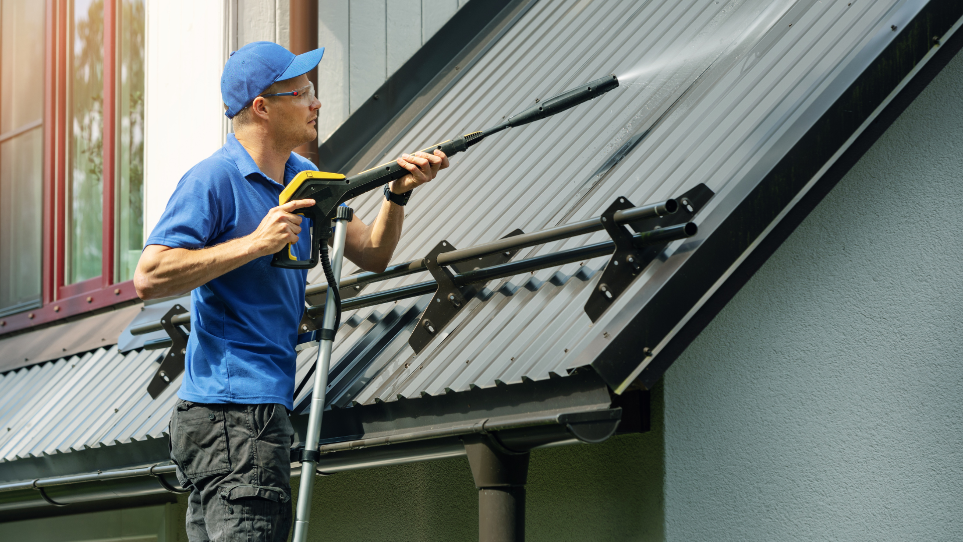 A man is cleaning the roof with a high pressure washer