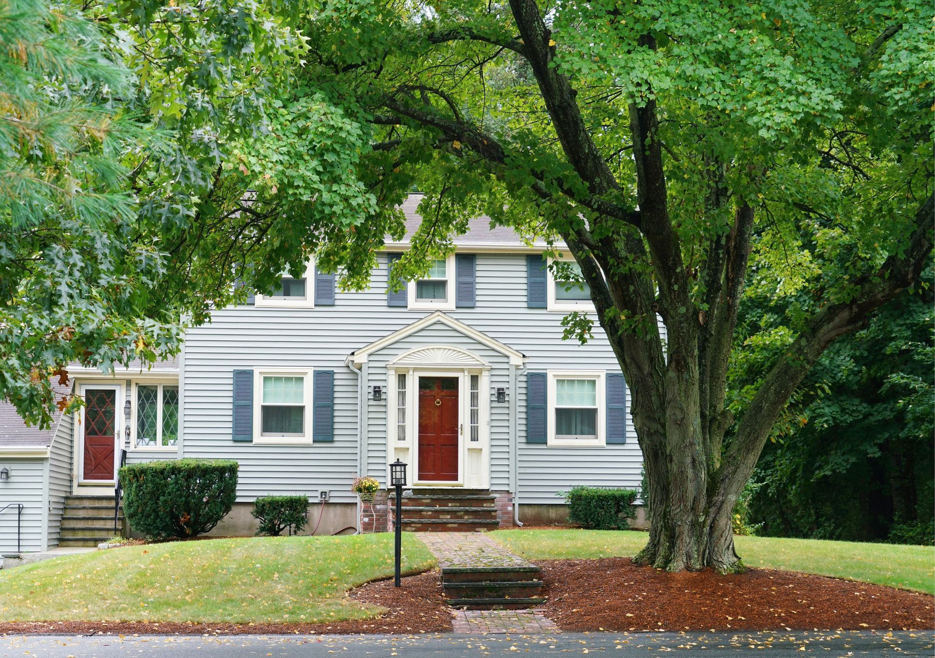 Two-story house with gray siding, blue shutters, and red front door.