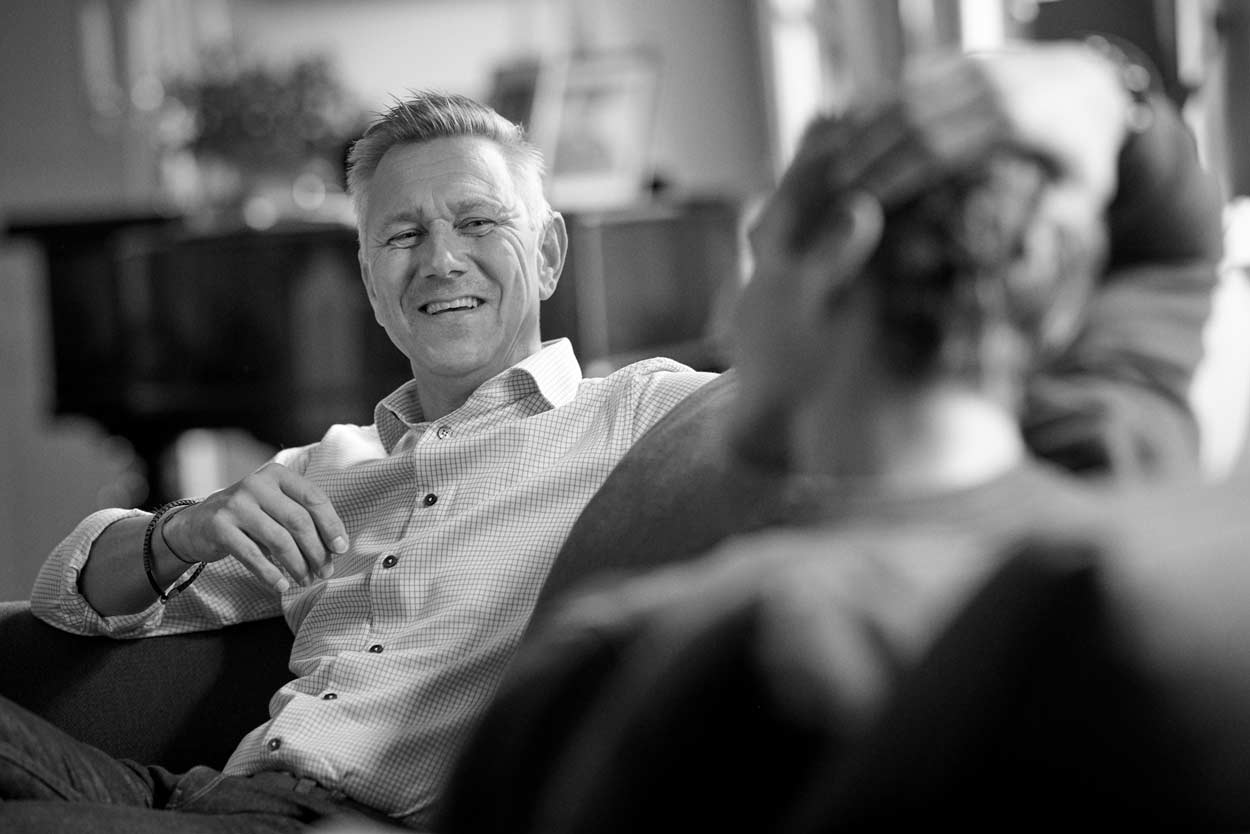 En man sitter i en soffa och pratar med en elev.