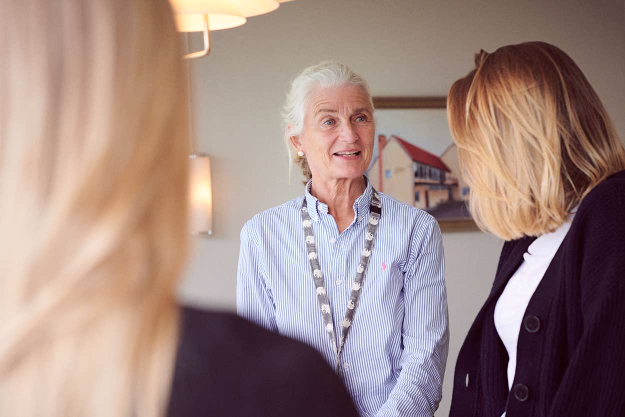 Tre kvinnor står bredvid varandra och pratar i ett rum.