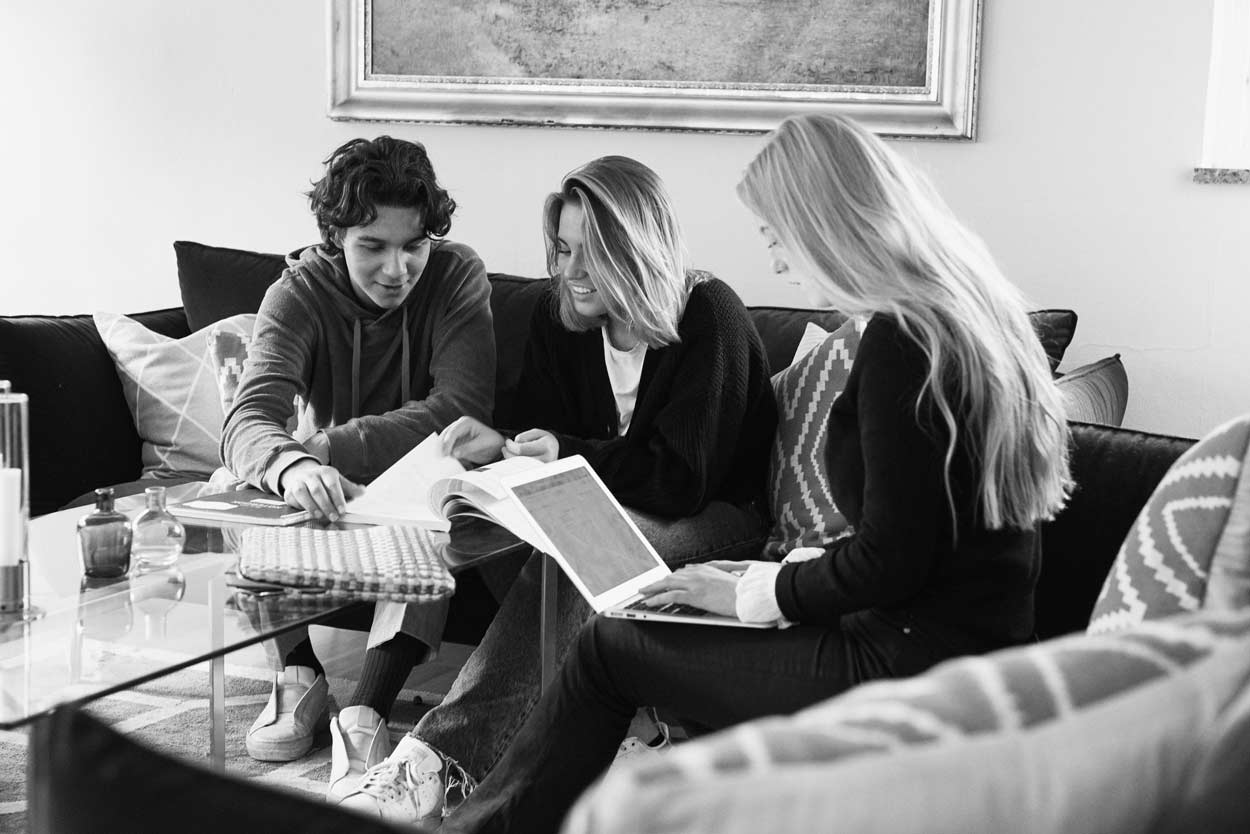 En grupp människor sitter i en soffa och tittar på en bärbar dator.