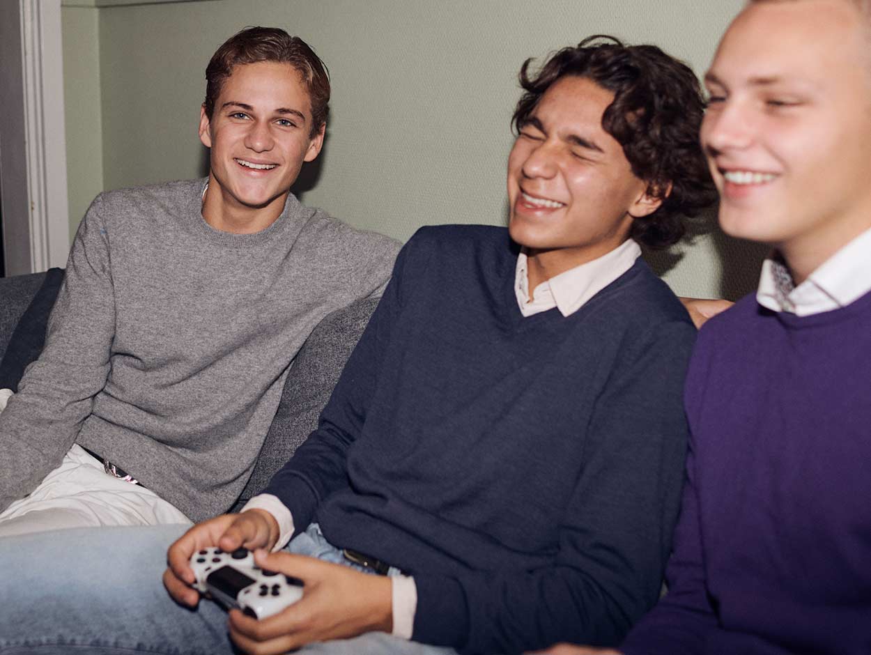 Tre unga män sitter i en soffa och spelar ett tv-spel