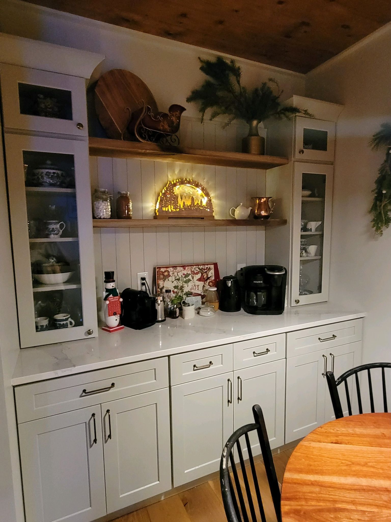 A kitchen with white cabinets and a wooden table and chairs.
