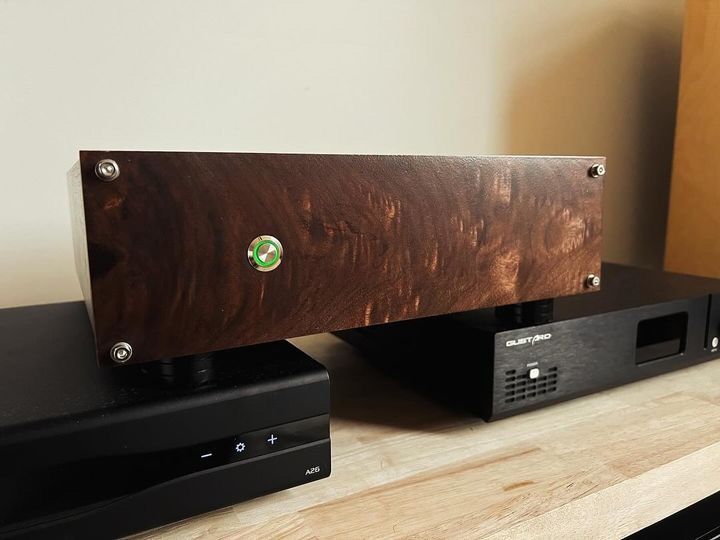 A wooden box is sitting on top of a wooden table next to a black box.
