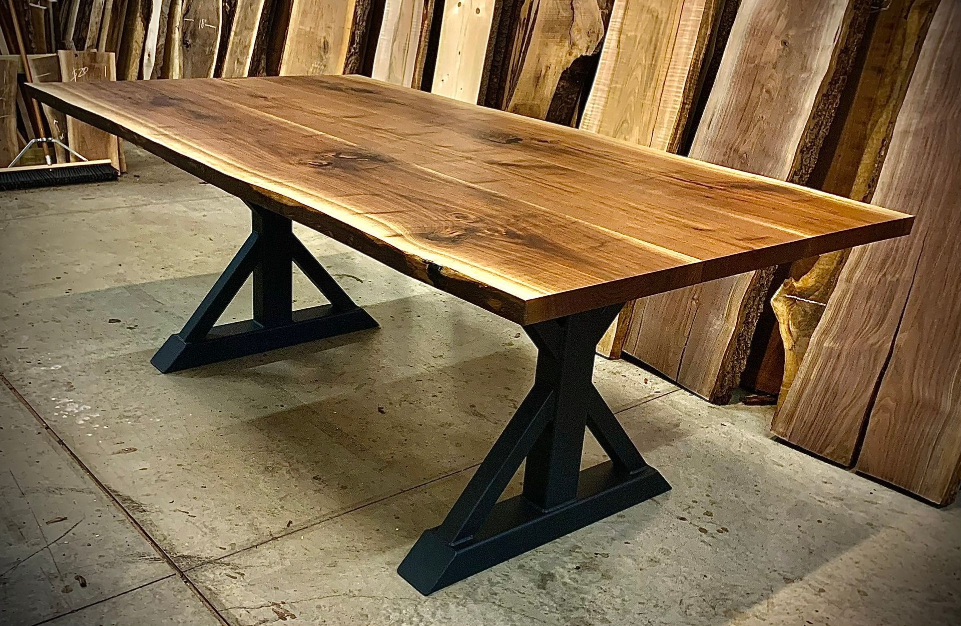 A wooden table with a metal base is sitting on a concrete floor.