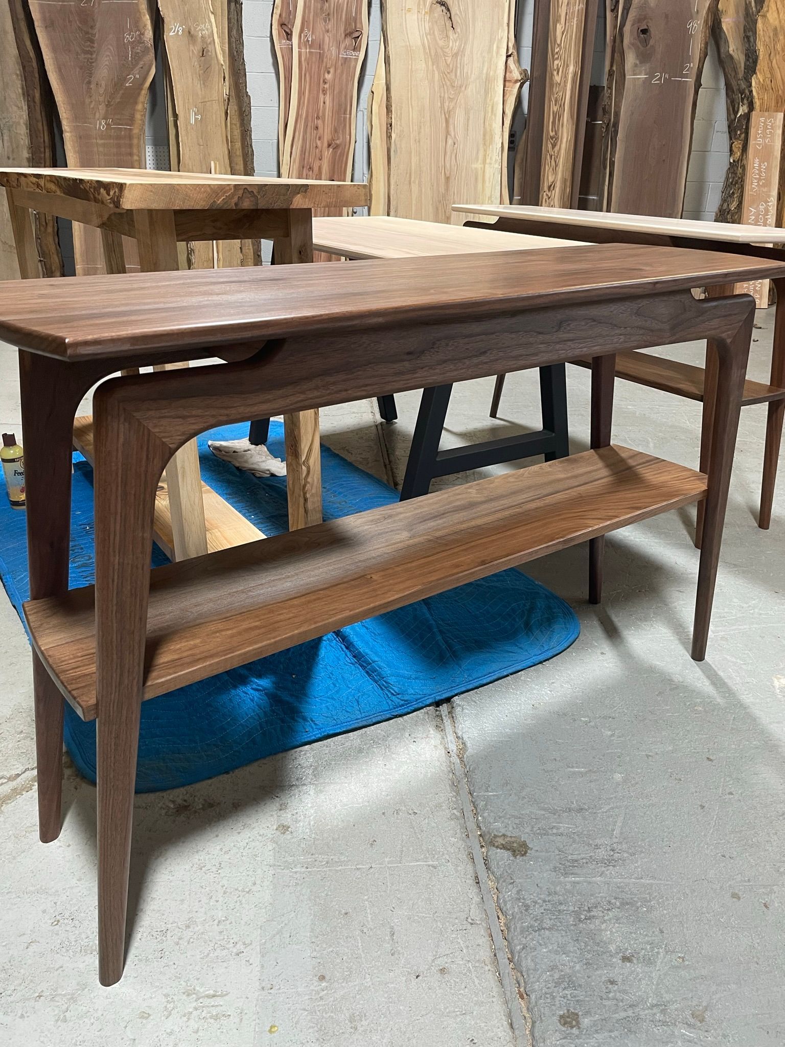 A wooden table with a shelf underneath it is sitting on a concrete floor.