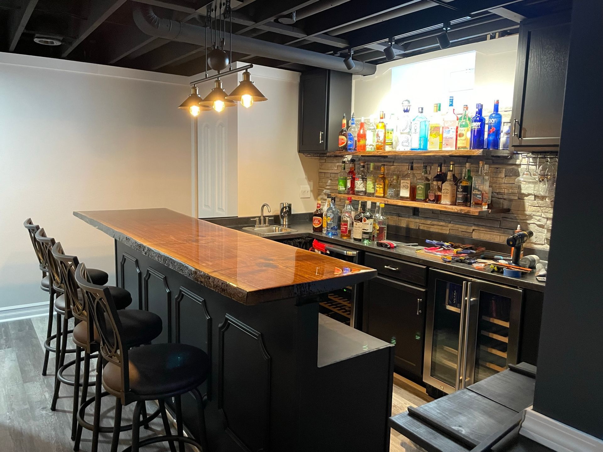 A bar in a basement with lots of bottles on the shelves.