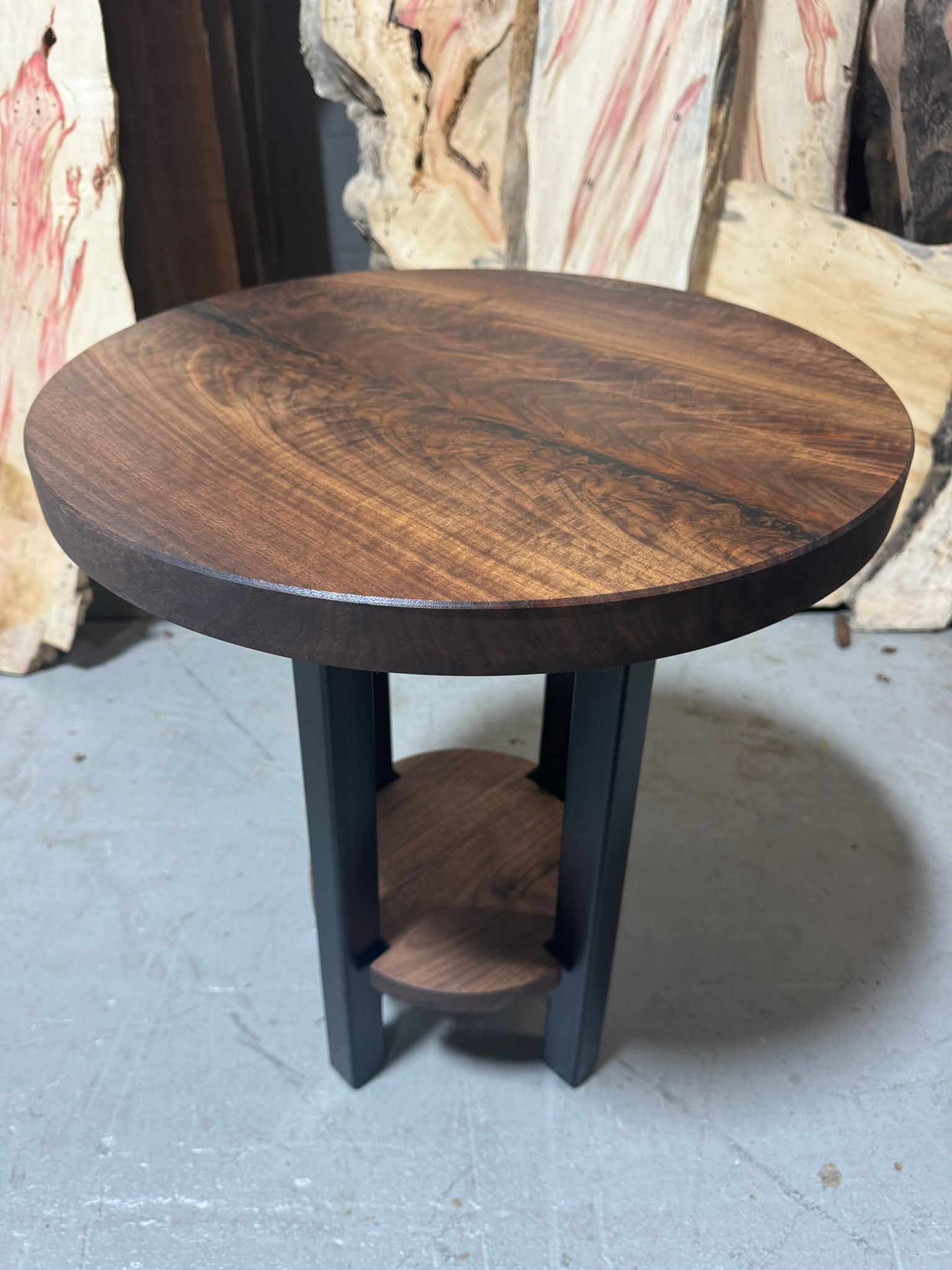 A round wooden table with a shelf underneath it.