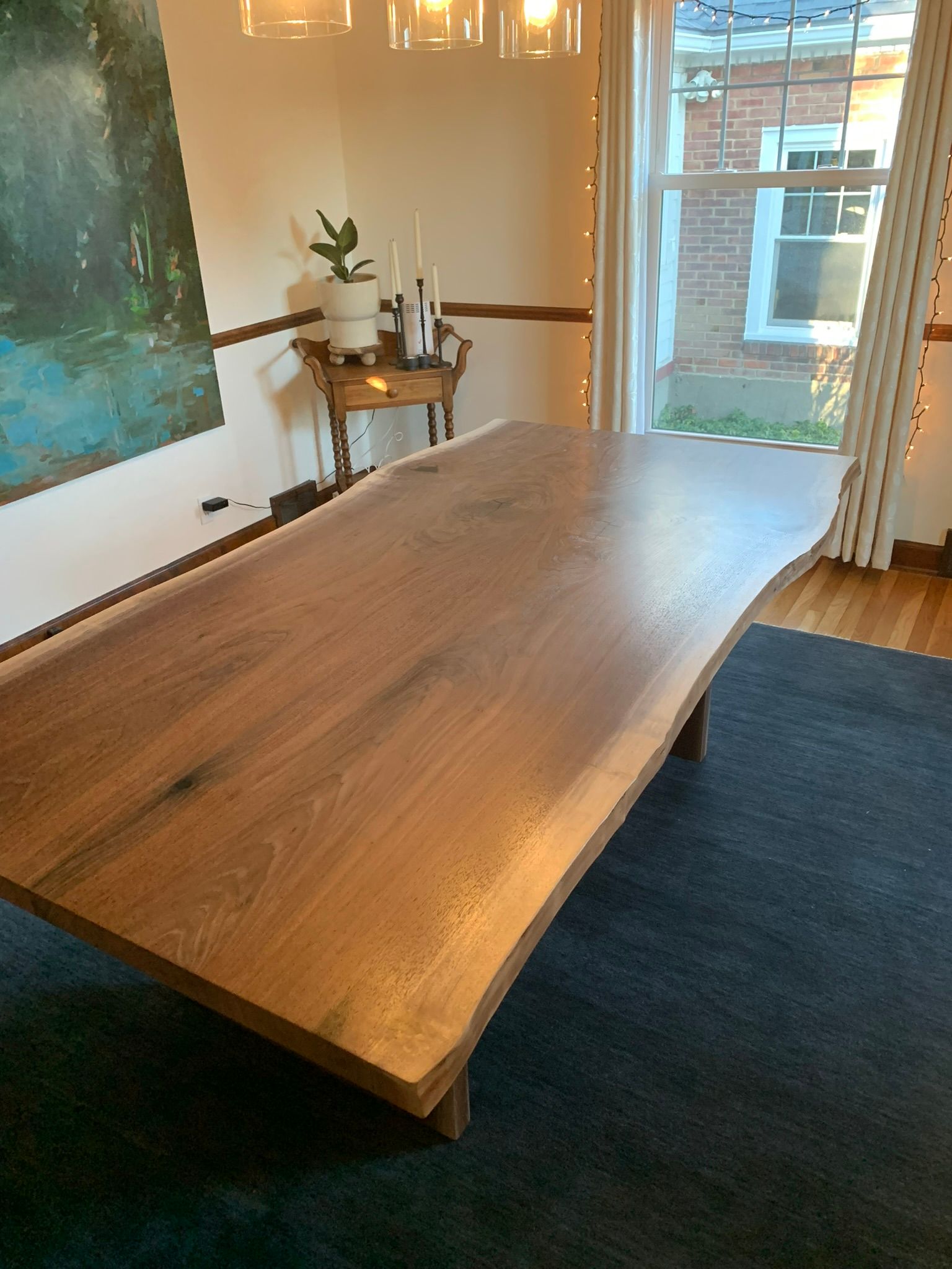 A large wooden table is sitting in a dining room next to a window.
