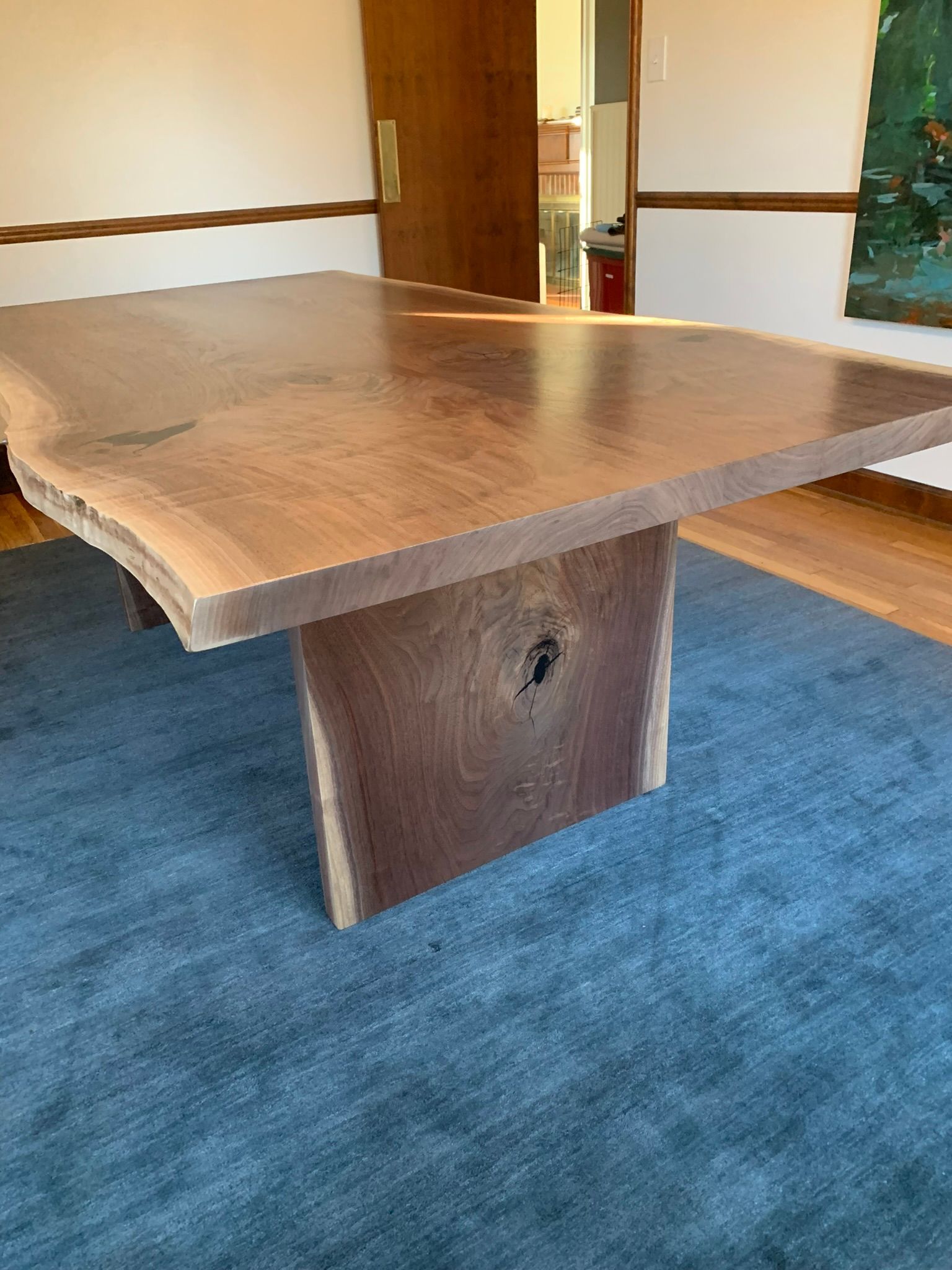 A wooden table is sitting on top of a blue rug in a room.