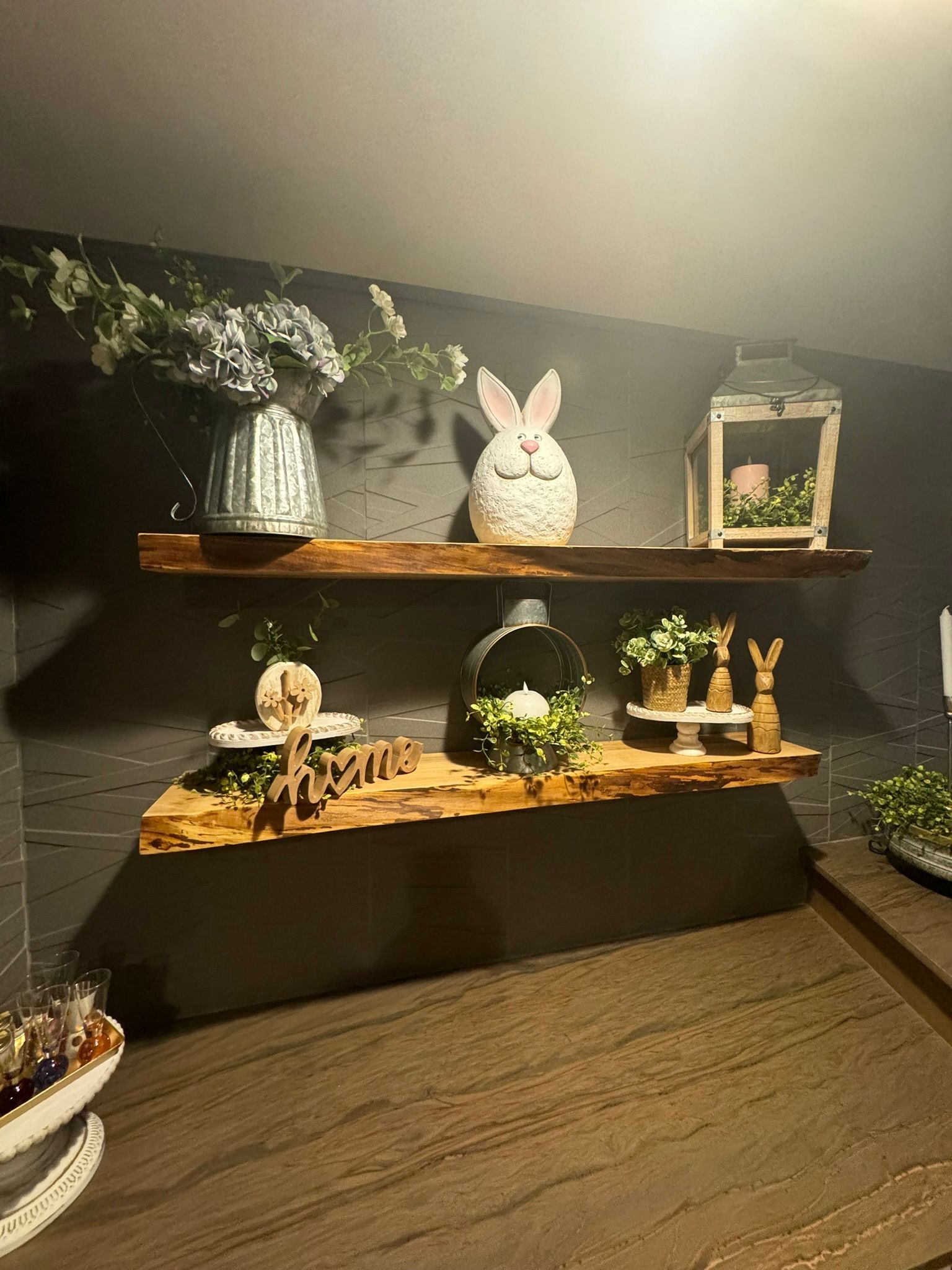 A room with three wooden shelves filled with flowers and decorations.