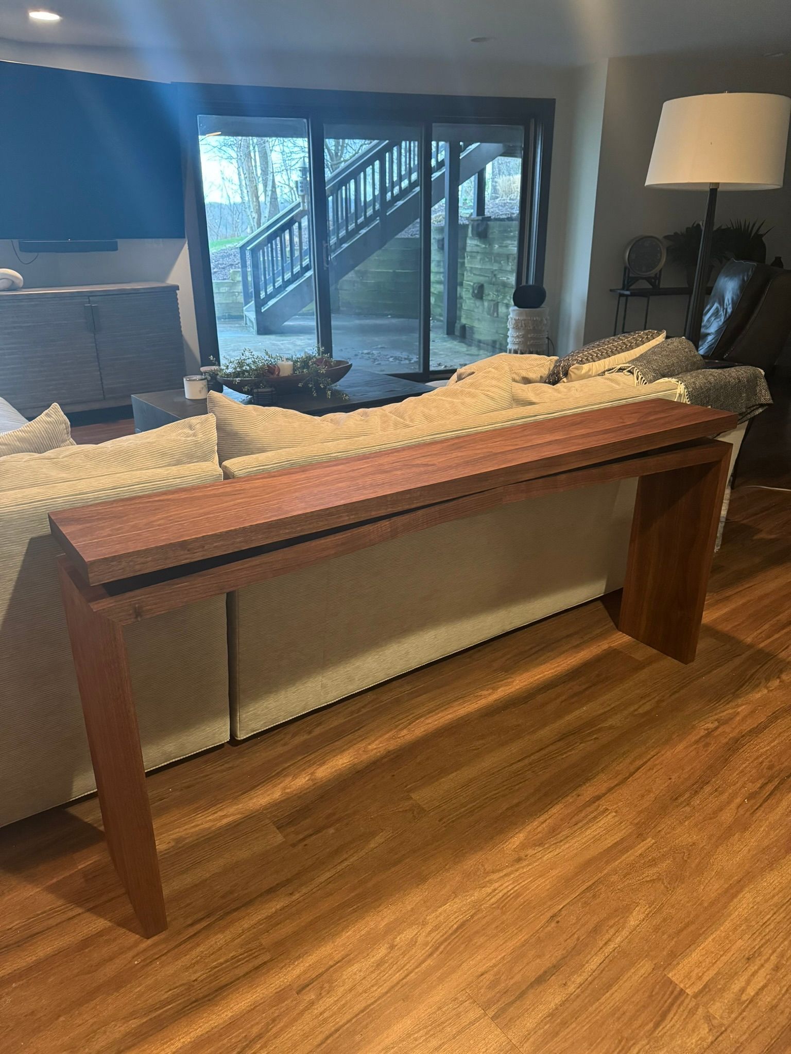 A long wooden table is sitting in a living room next to a couch.