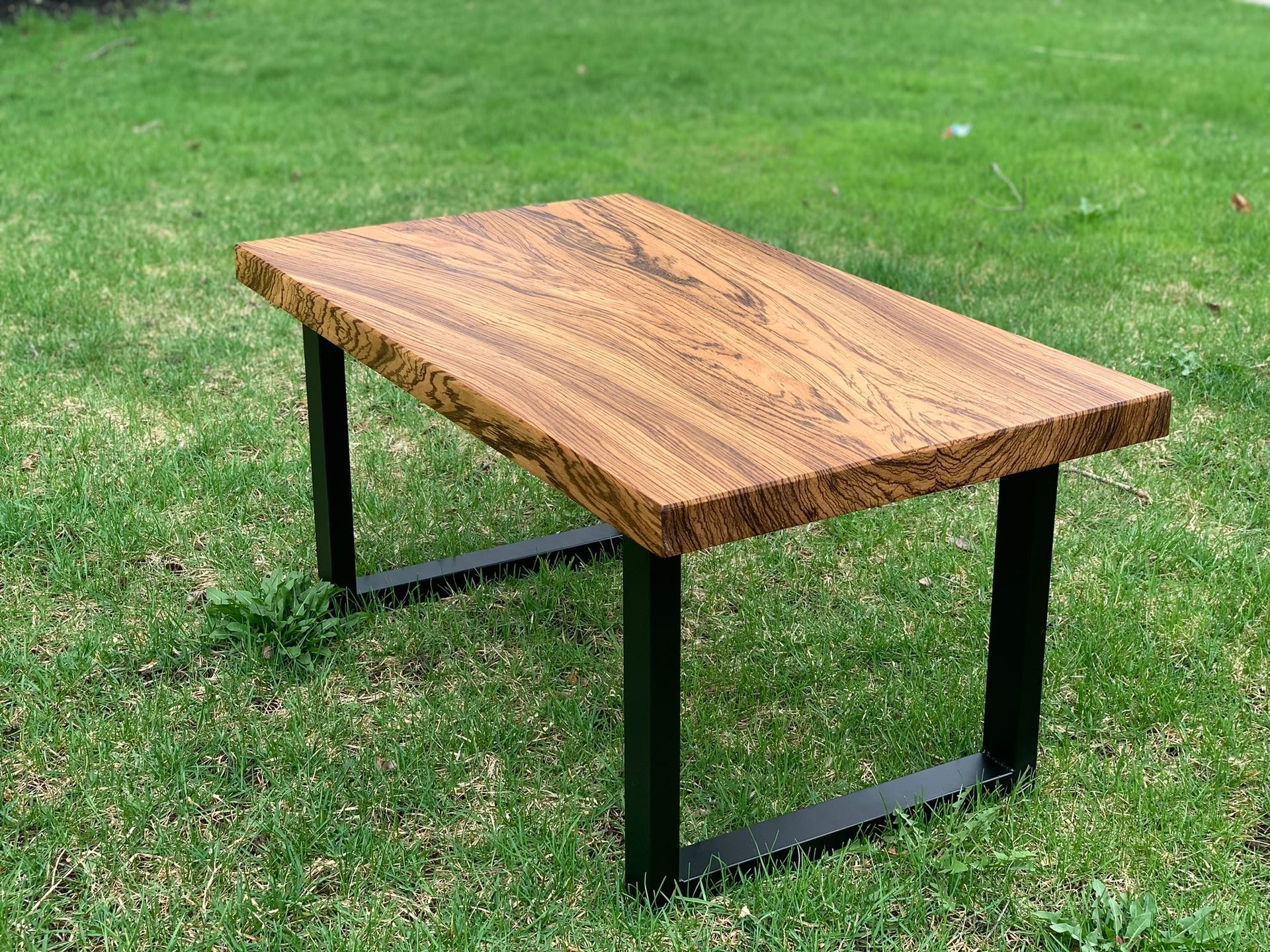 A wooden table is sitting on top of a lush green field.