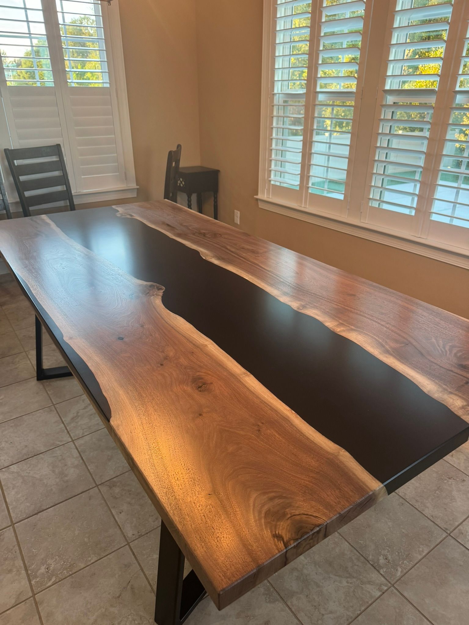 A wooden table with a river in the middle is sitting in a room next to a window.