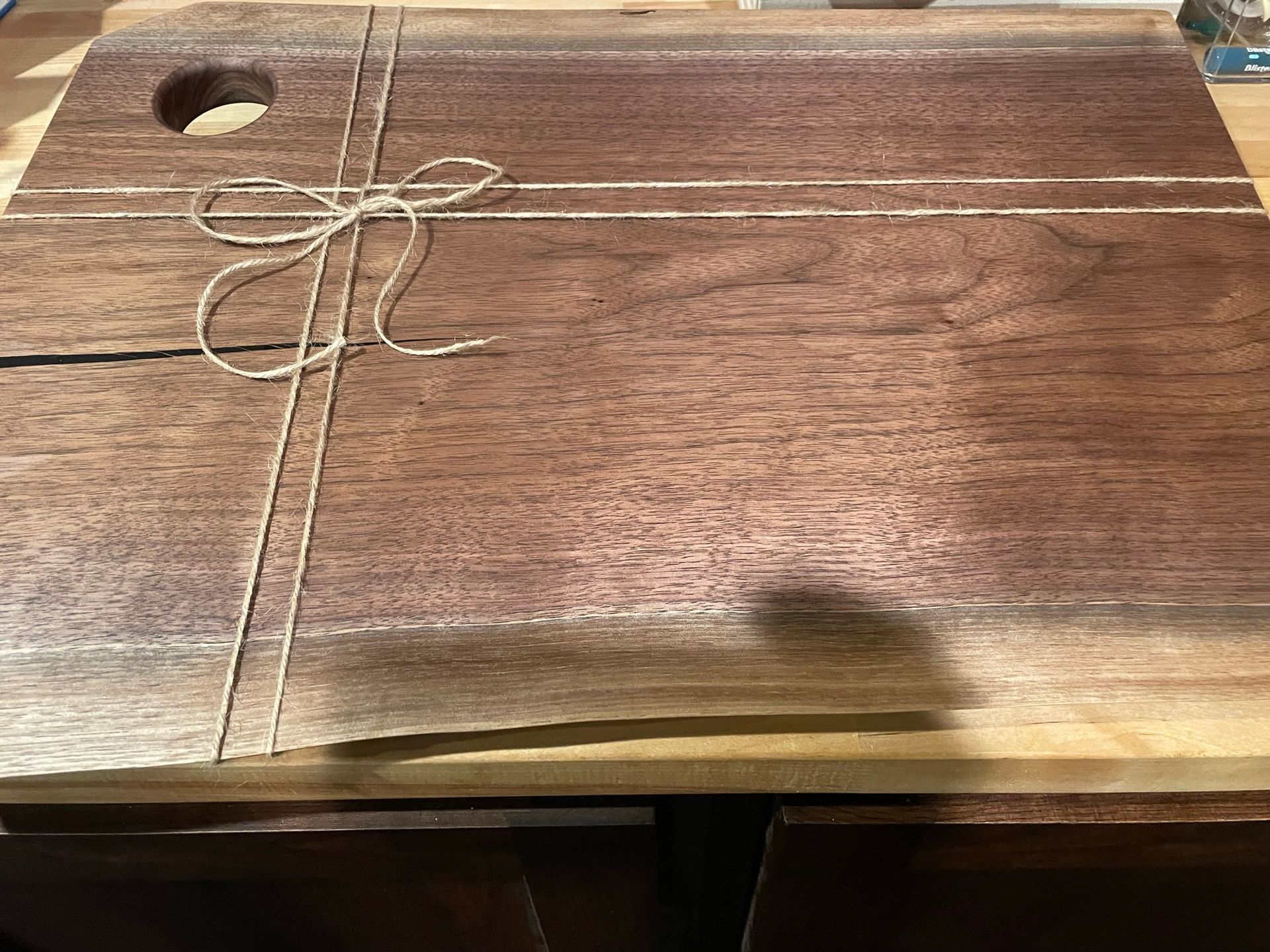 A wooden cutting board with a hole in the middle is tied with string.
