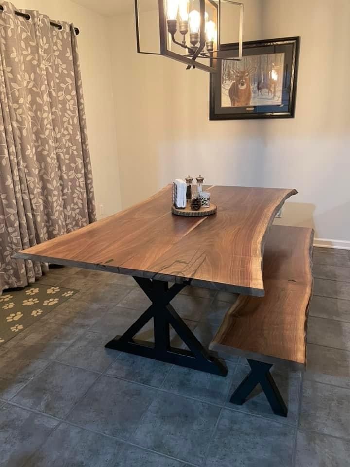 A wooden table and bench in a dining room with a picture on the wall.