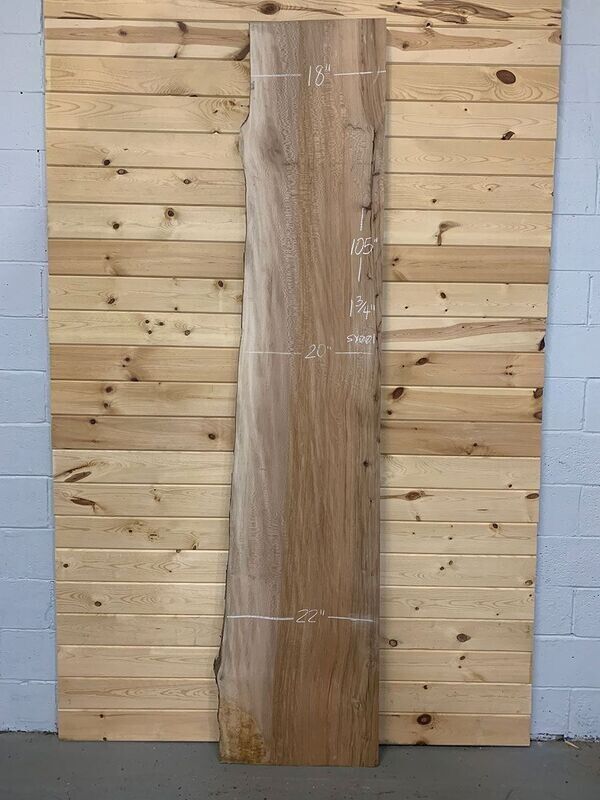 A large piece of wood is sitting in front of a wooden wall.