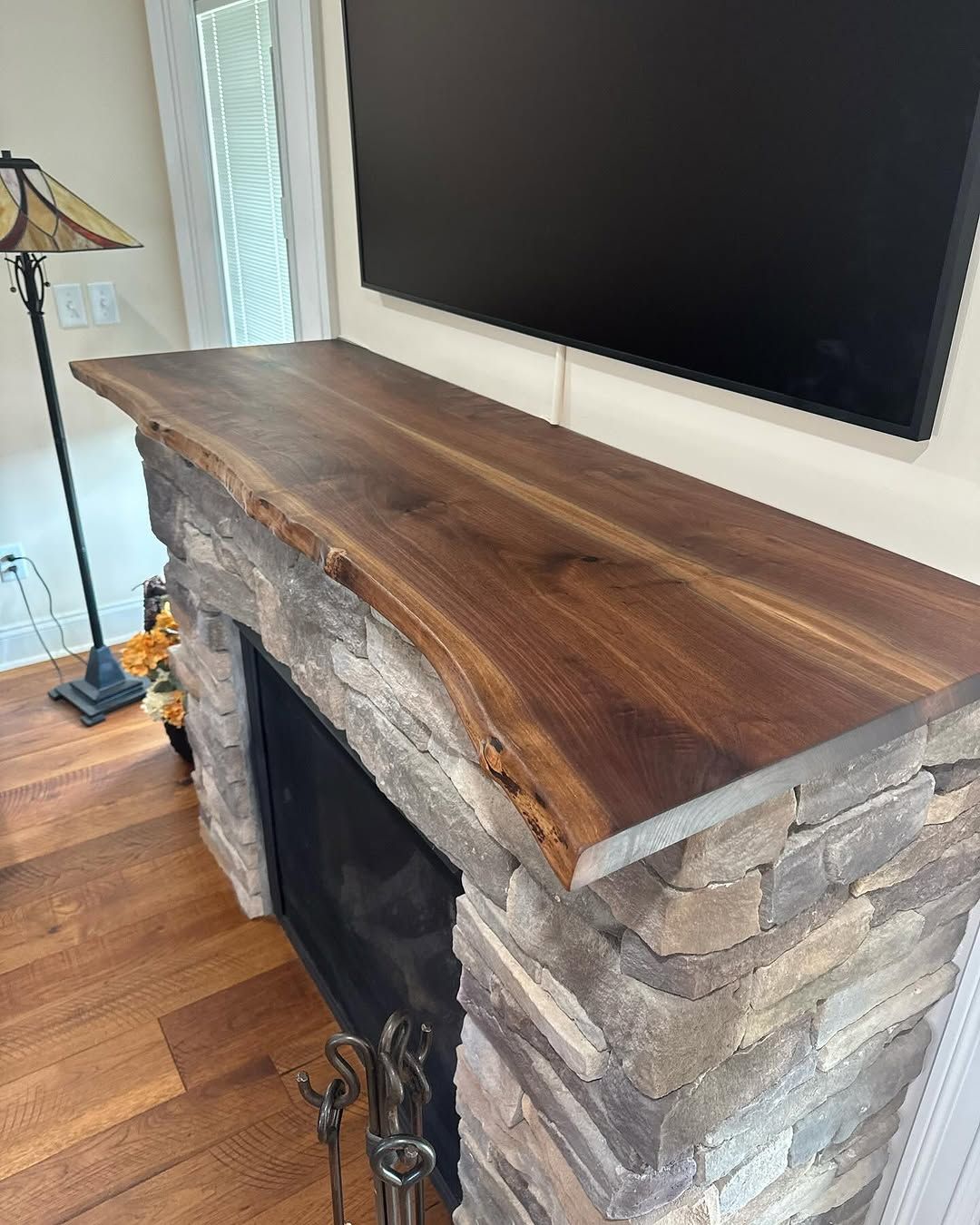 A fireplace with a wooden mantle and a flat screen tv mounted on the wall.